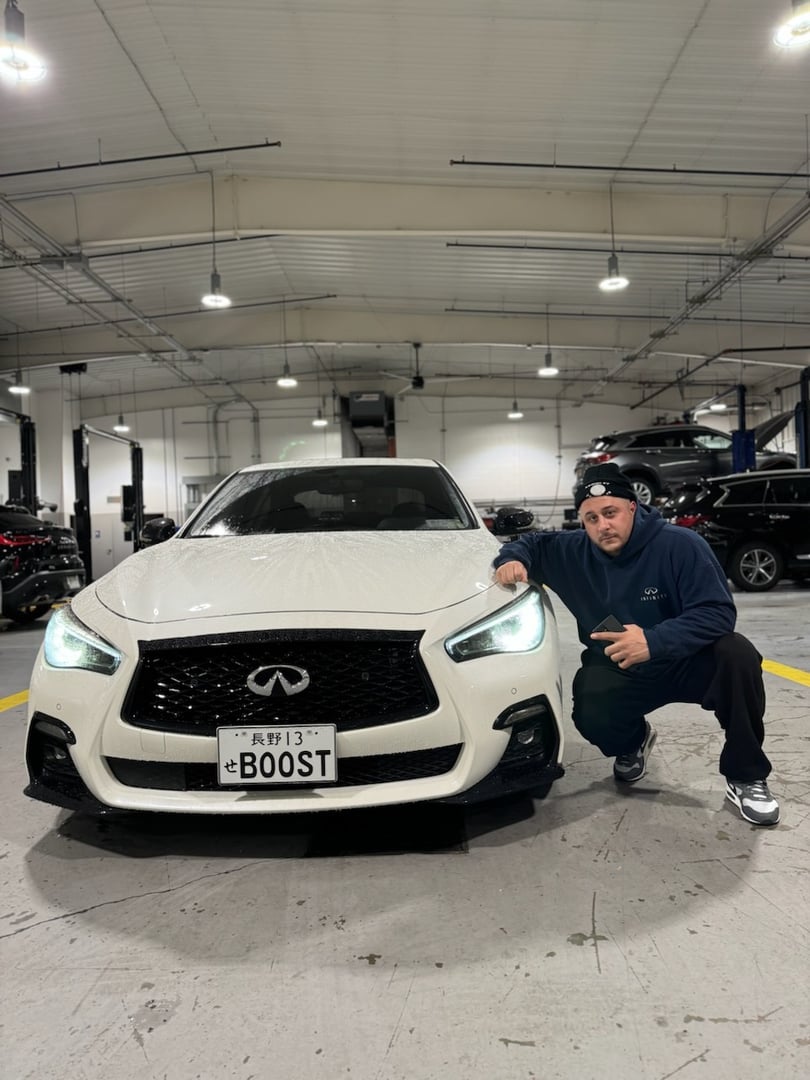 Smiling mechanic using a digital tablet next to a car on a hydraulic lift in a auto repair shop