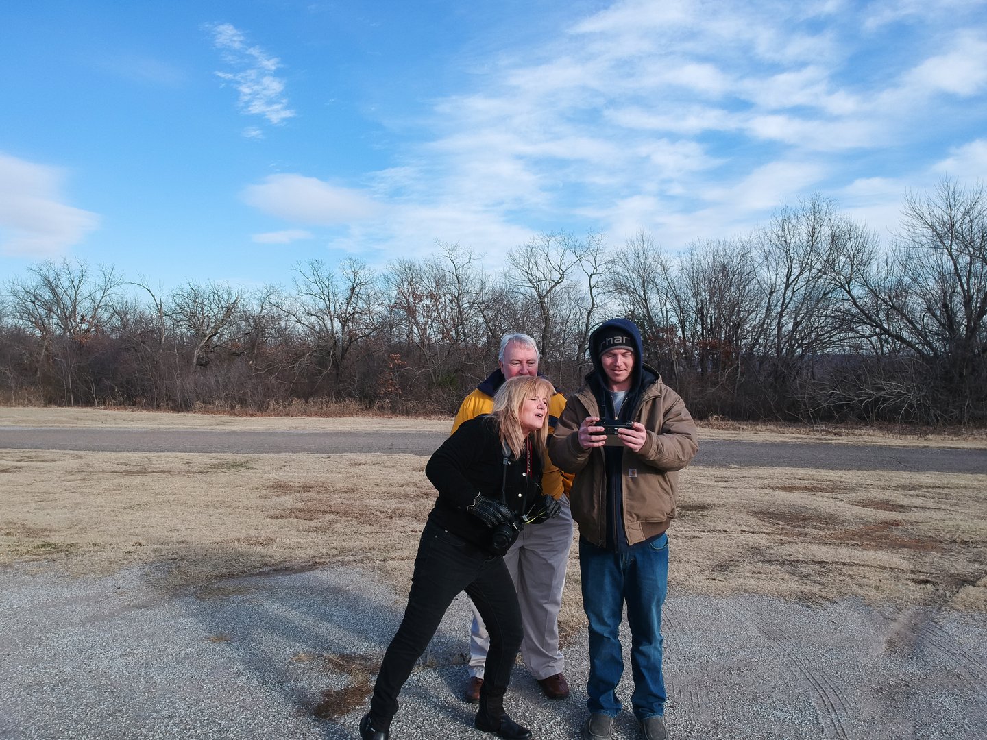 Family group flying drone with controller dressed in winter clothing against bare winter trees Tulsa Oklahoma USA12 - 28- 2017