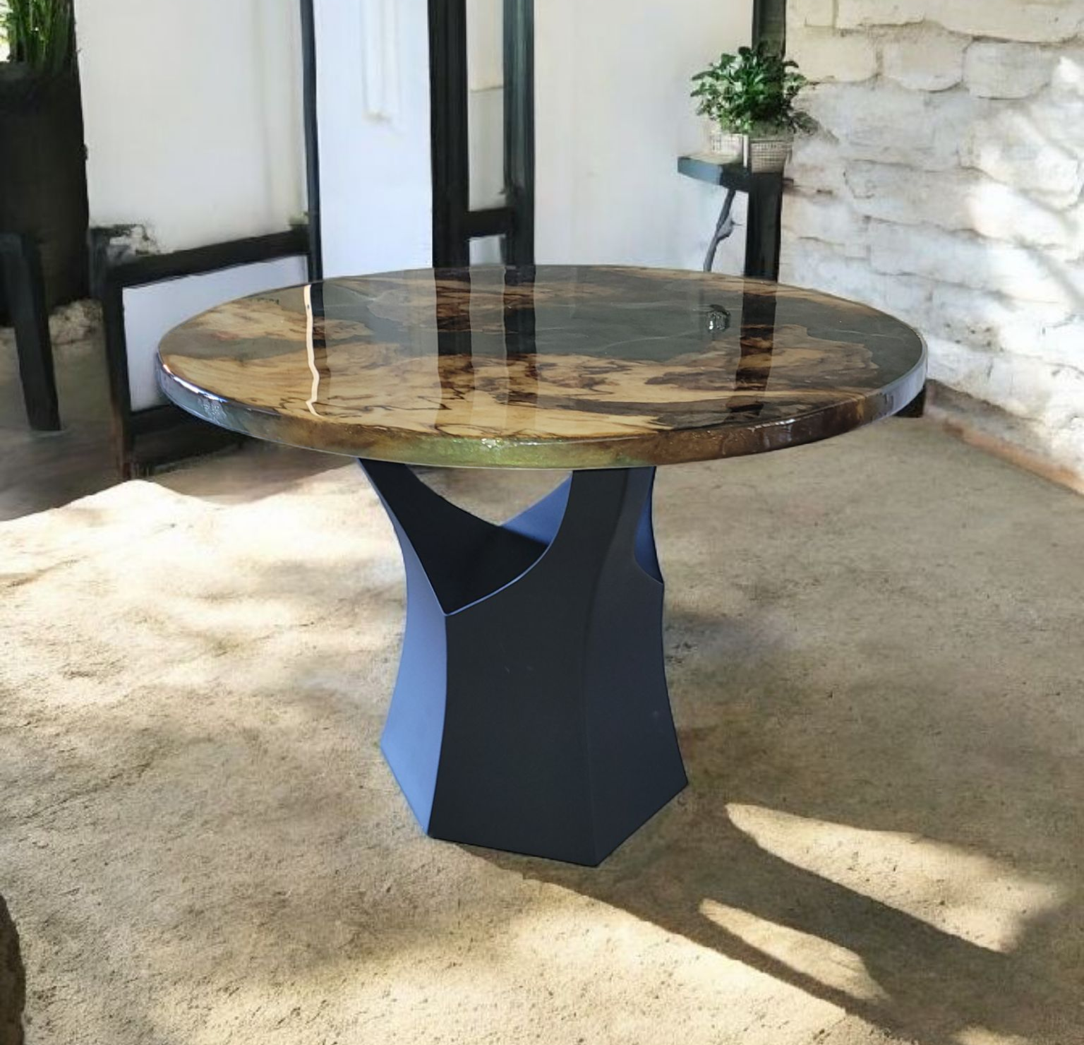 A round table with a glossy marbled top and geometric black base on a beige rug in a modern room.