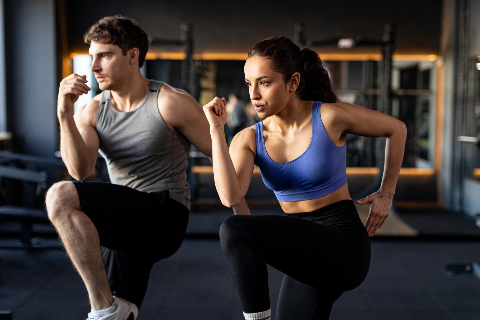 Focused sportive couple doing warm up exercises during fitness workout in modern gym