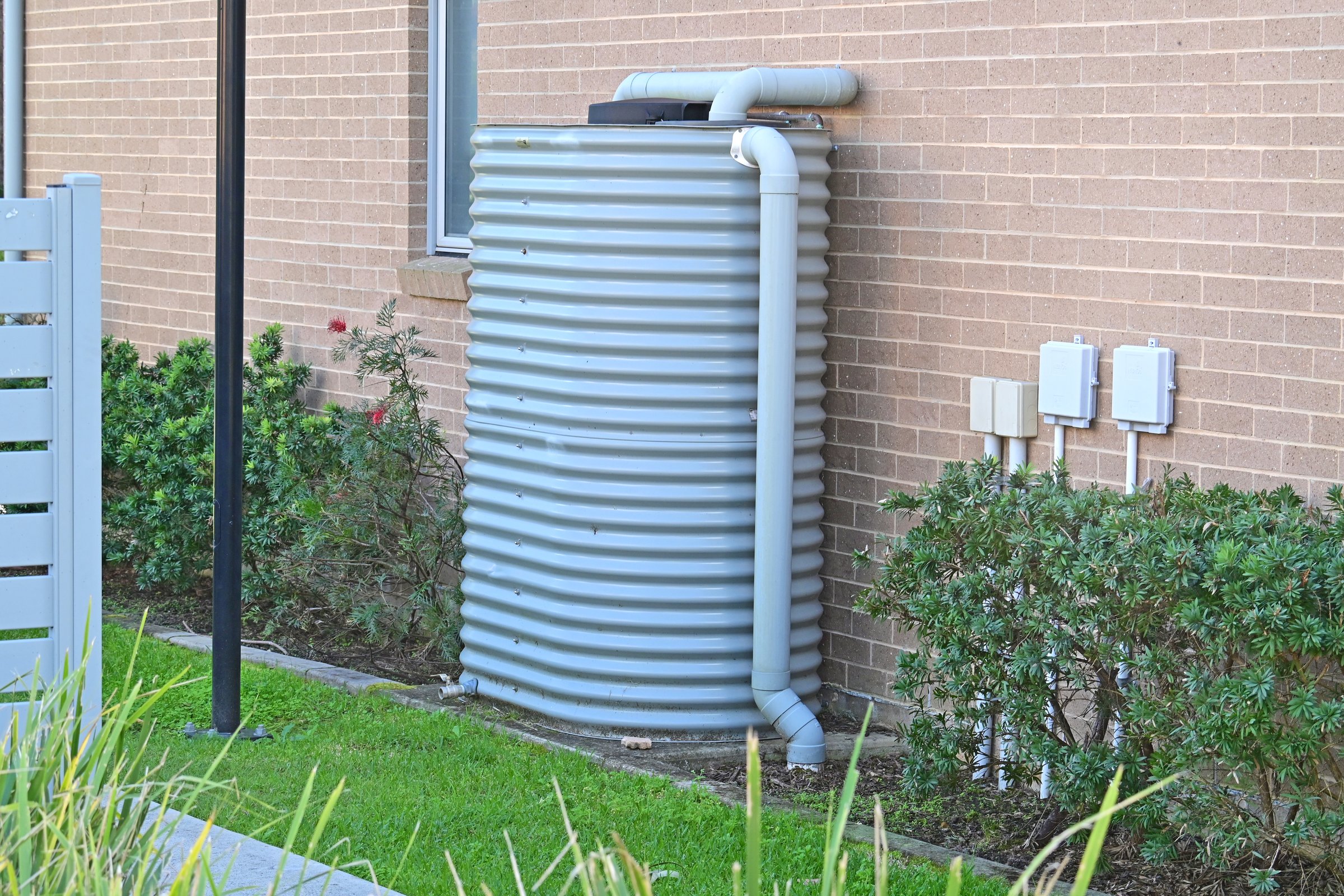 Rainwater storage tank on the side of a brick house with plumbing