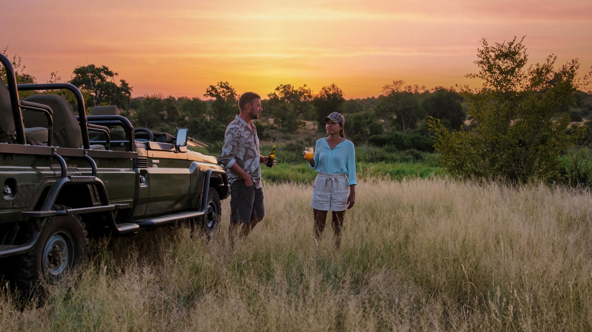 Couples from different backgrounds immerse themselves in the beauty of Kruger National Park during a sunset safari. Sipping drinks, they revel in the tranquility of nature and wildlife.