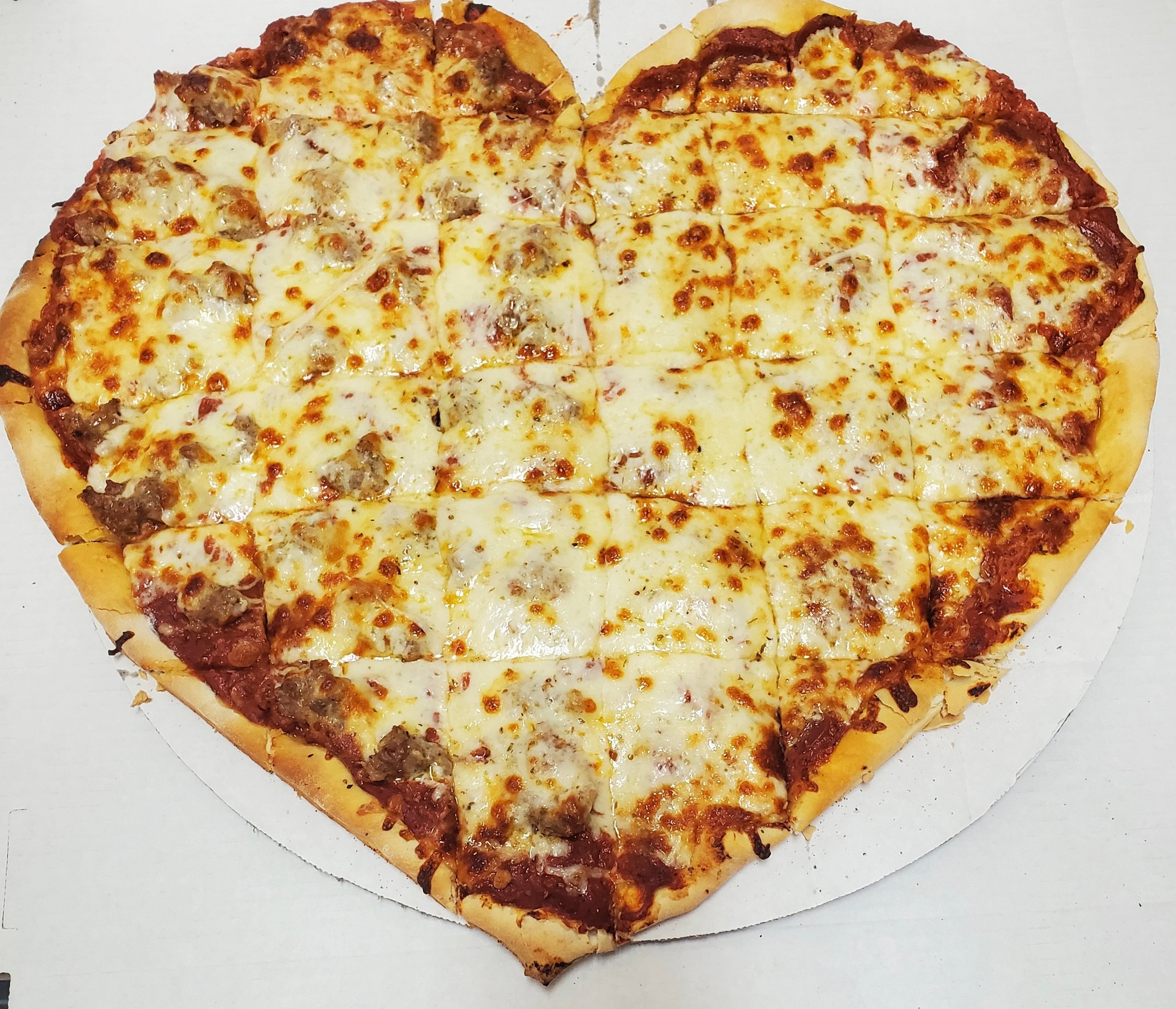 Heart-shaped cheese and pepperoni pizza cut into square slices on a white background.