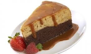 Slice of layered cake with caramel sauce on a white plate, garnished with strawberries.