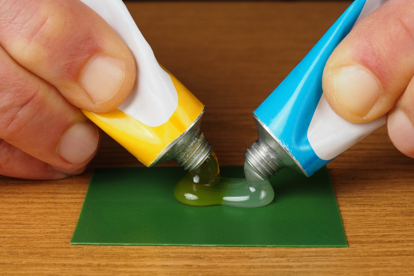 Hand holding two tubes with epoxy glue ingredients, resin and hardener