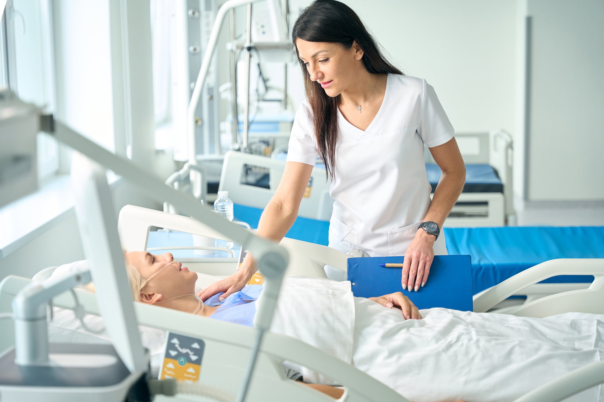 Caring female doctor encourages a lady after an operation, the patient lies on a special post-operative bed