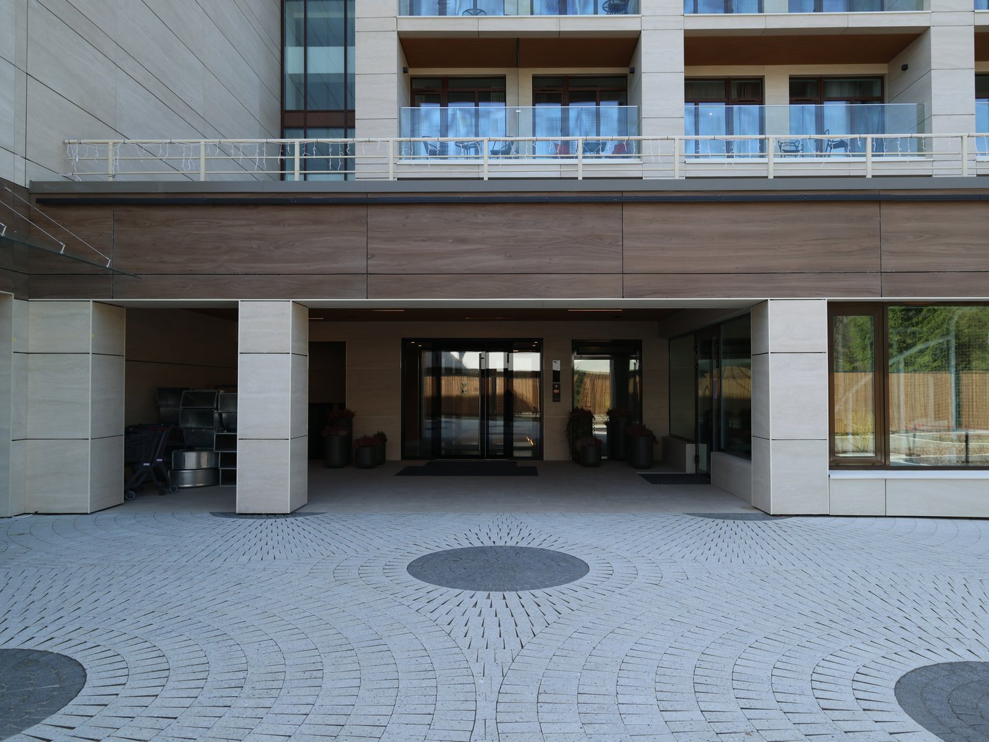 An elegant and sleek modern building entrance, featuring stylish wooden accents and beautifully landscaped surroundings