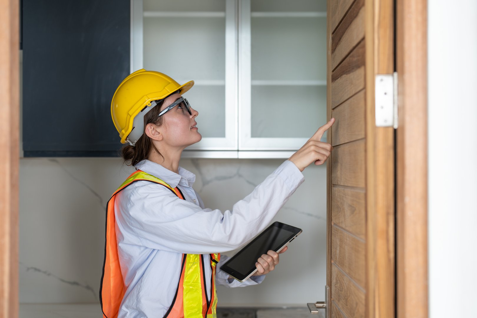 Woman construction engineer using tablet inspect wooden door in building site place. Female architect working at construction site