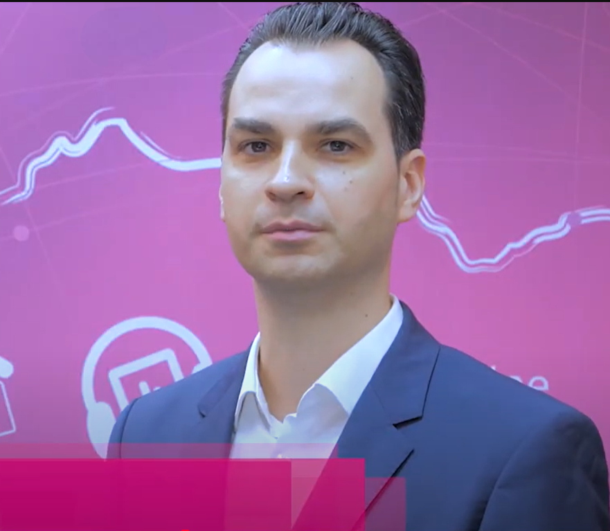 Man in a suit against a pink backdrop with abstract graphics and icons, reflecting a professional setting.