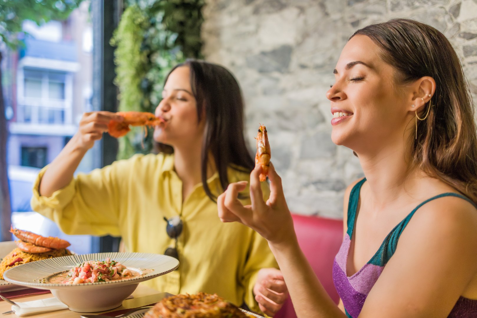 Two women savoring shrimps in an ecuadorian food restaurant located in madrid, spain, enjoying a traditional meal from portoviejo, manabi