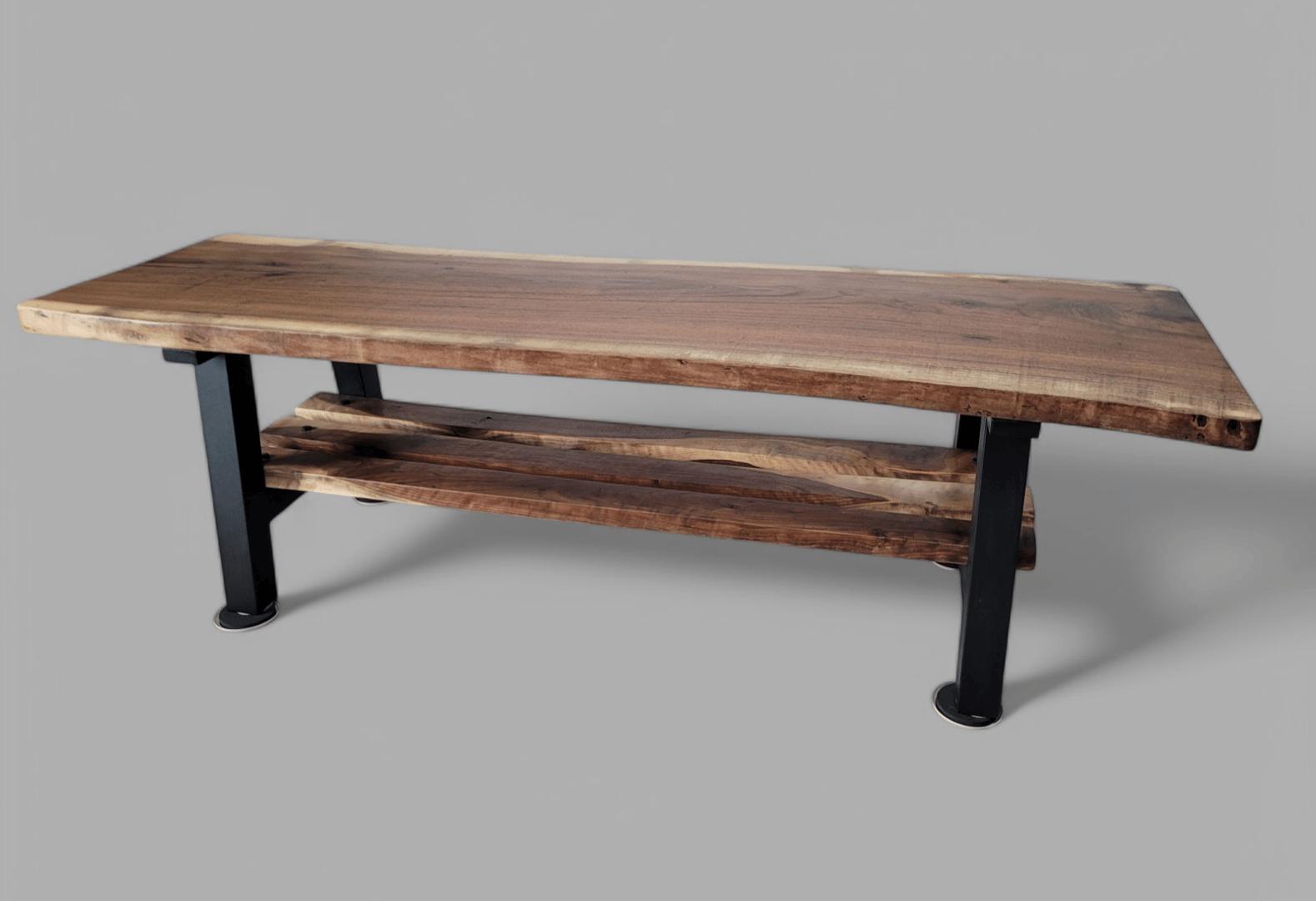 A wooden bench with a natural edge and a metal frame, featuring a lower shelf, set against a plain background.