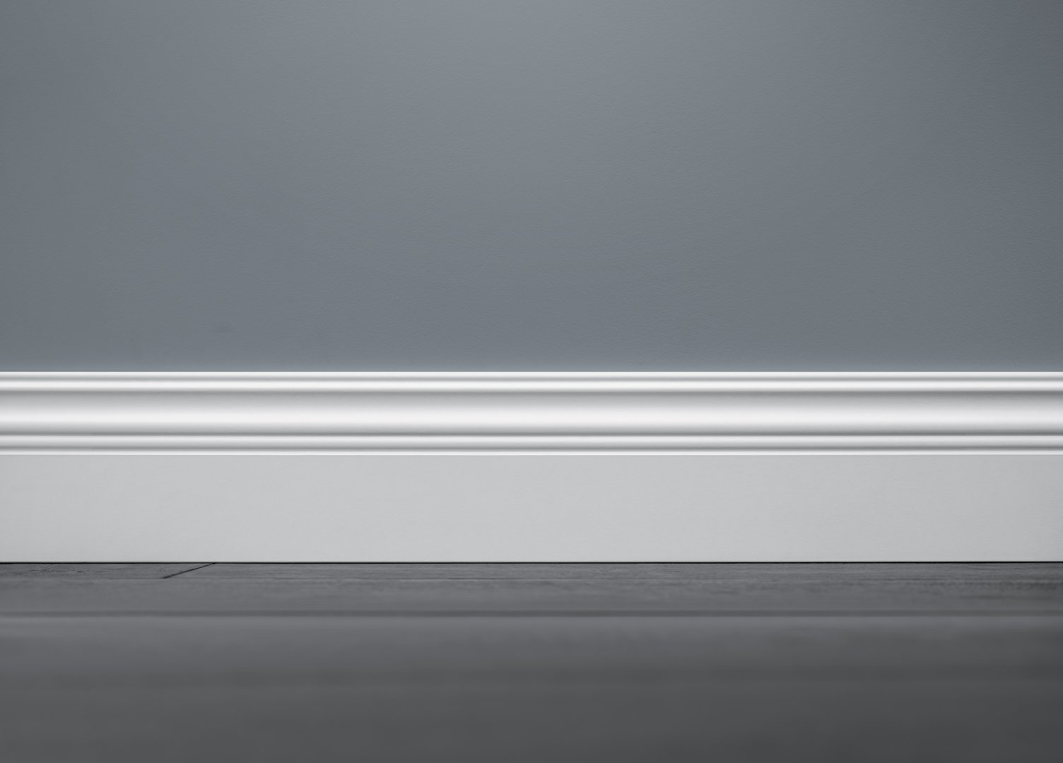 Close up of decorative, moulding white baseboard in empty room with copy space