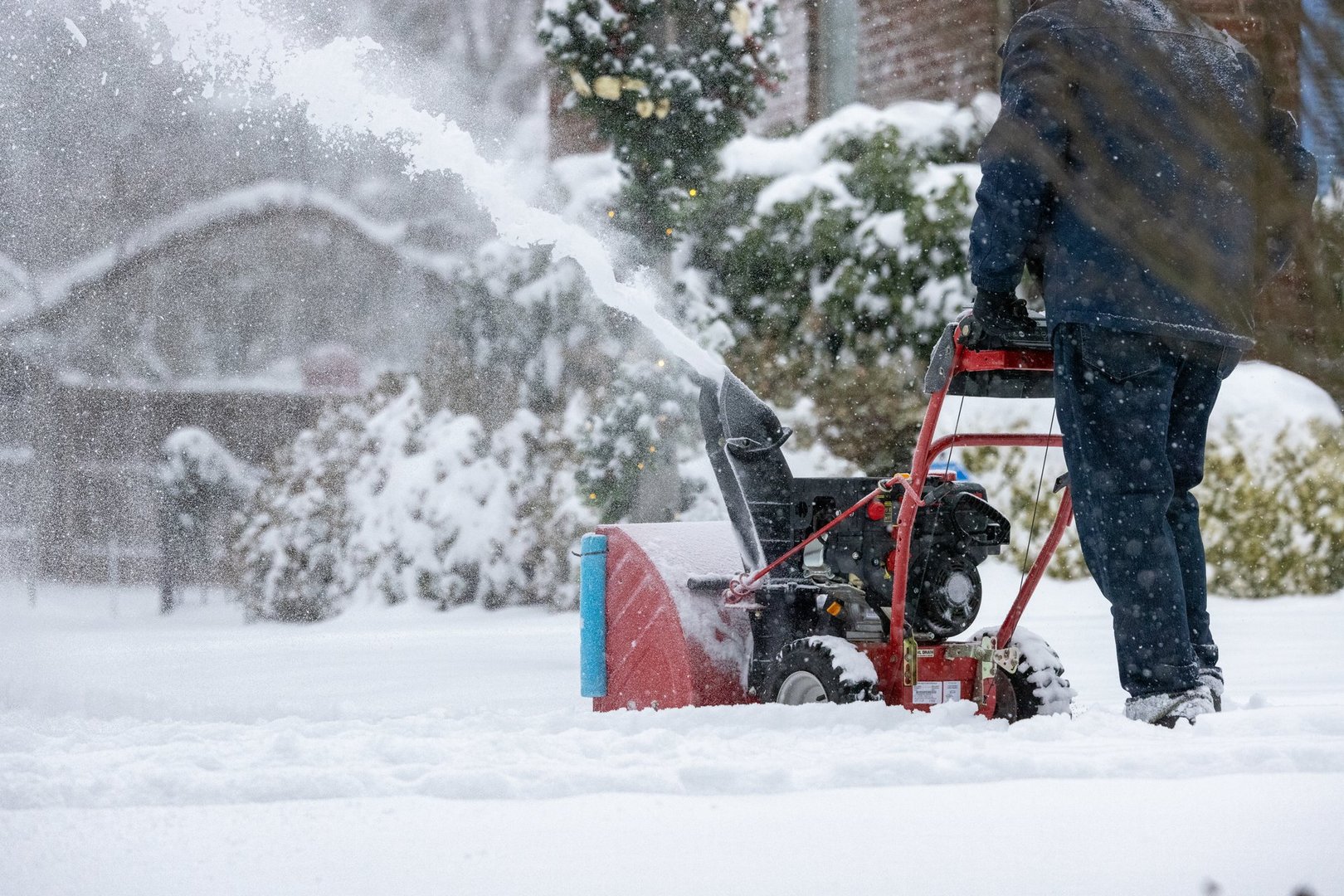 Homeowner using snowblower to clear driveway and sidewalks following big snowfall