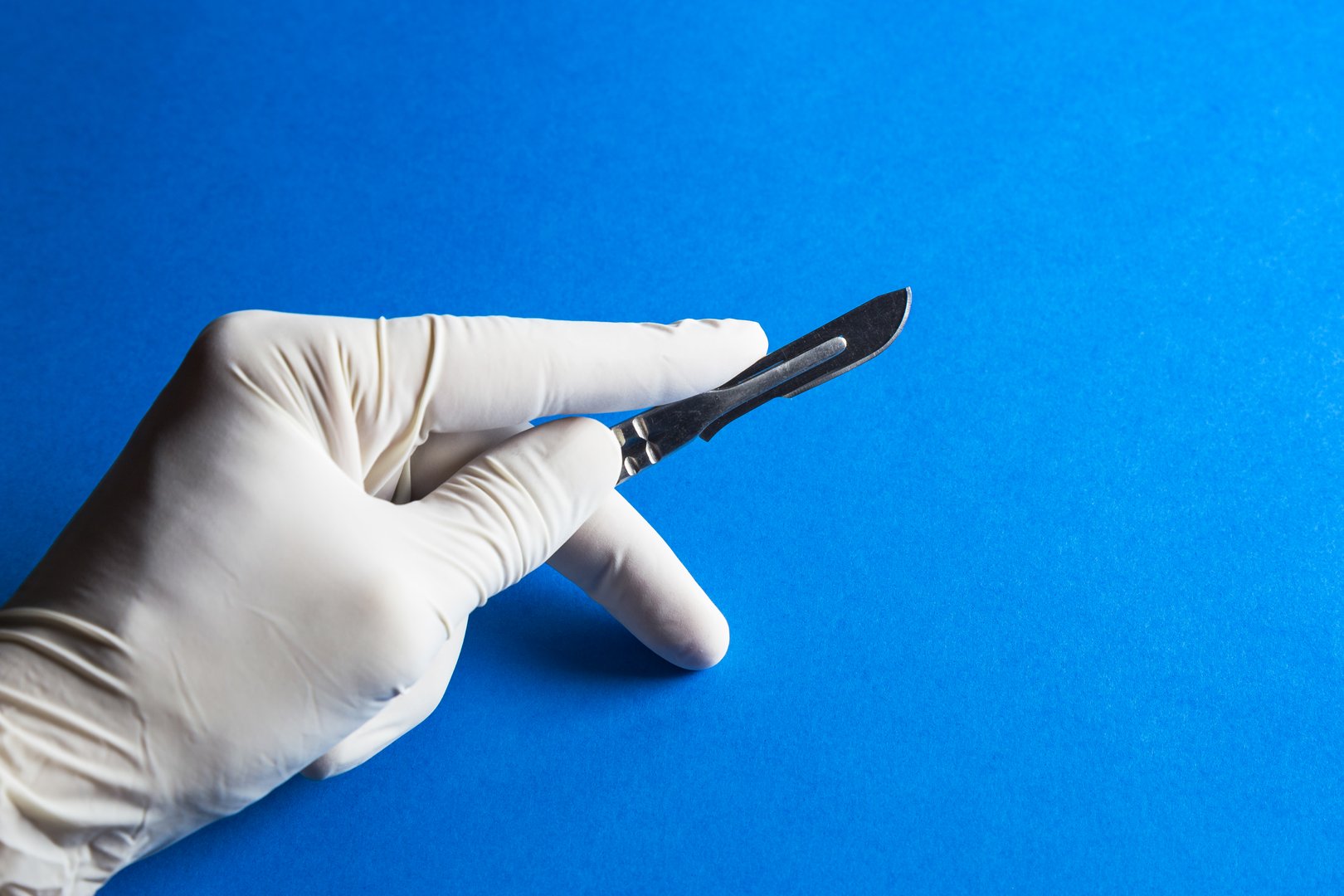 Medical scalpel in a hand with rubber glove
