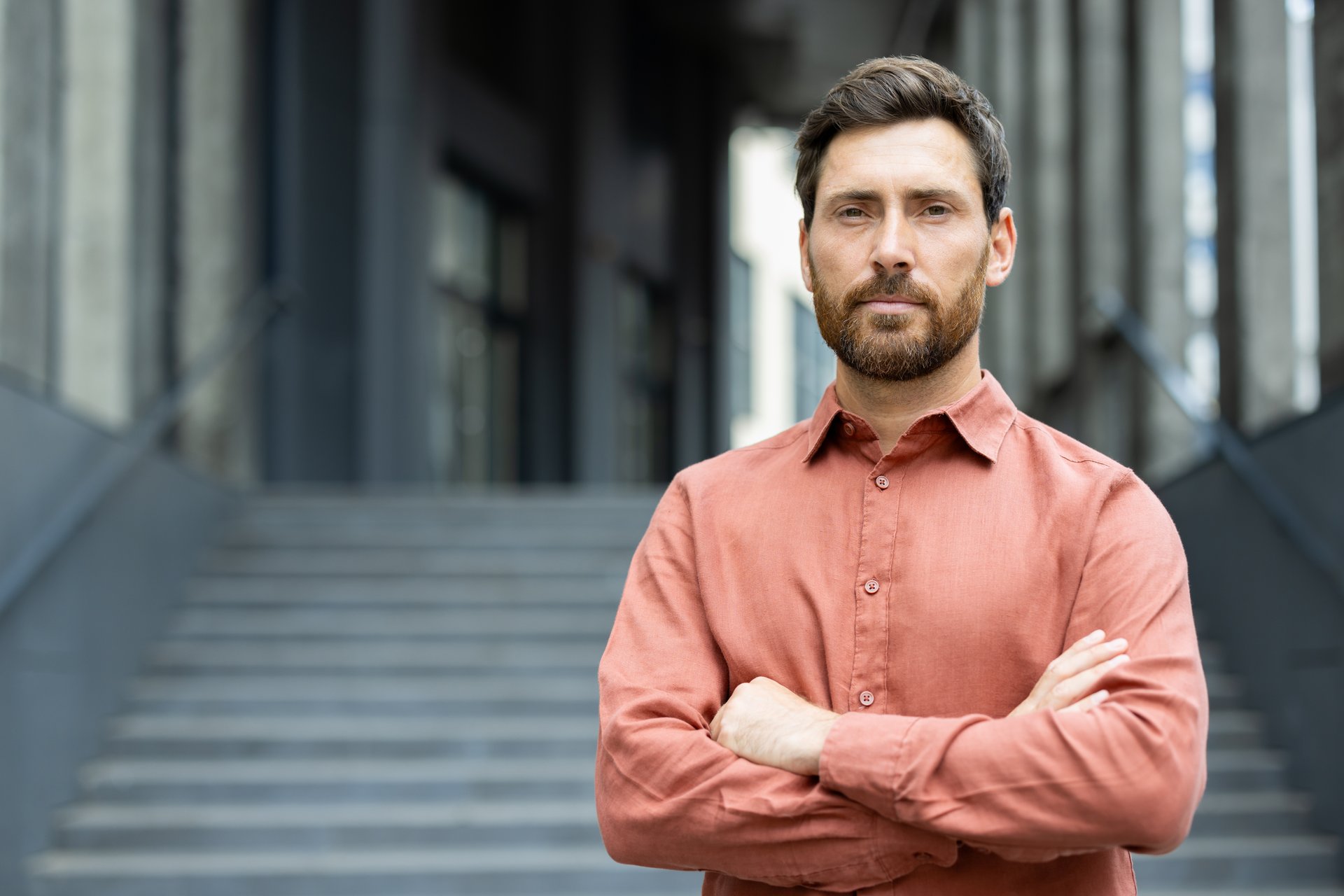 Portrait of a serious confident businessman outside an office building, man with crossed arms looking confidently at the camera