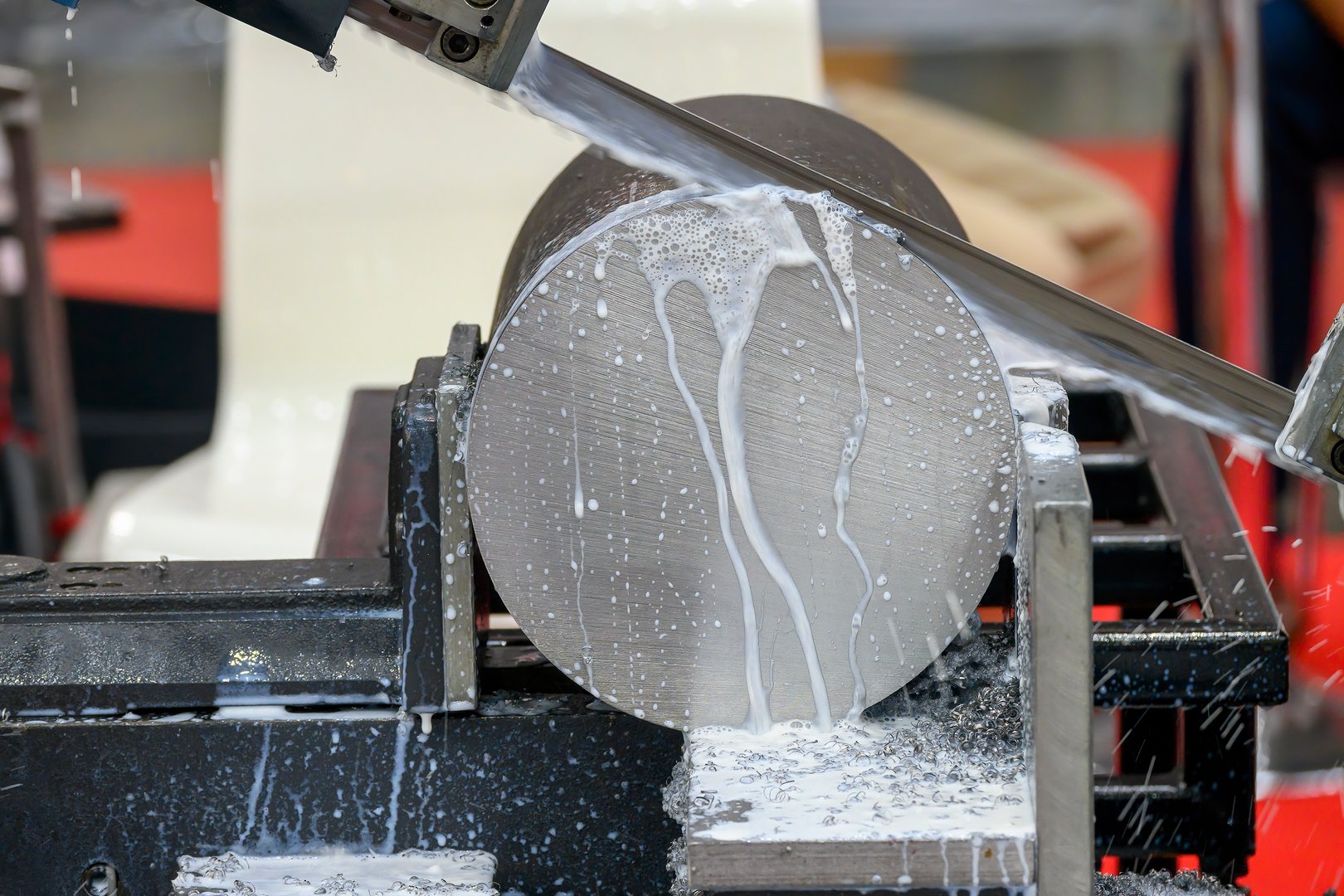 Close up scene the operation of band saw cutting machine cutting the metal shaft parts with coolant method. The machine tool for industrial purpose.