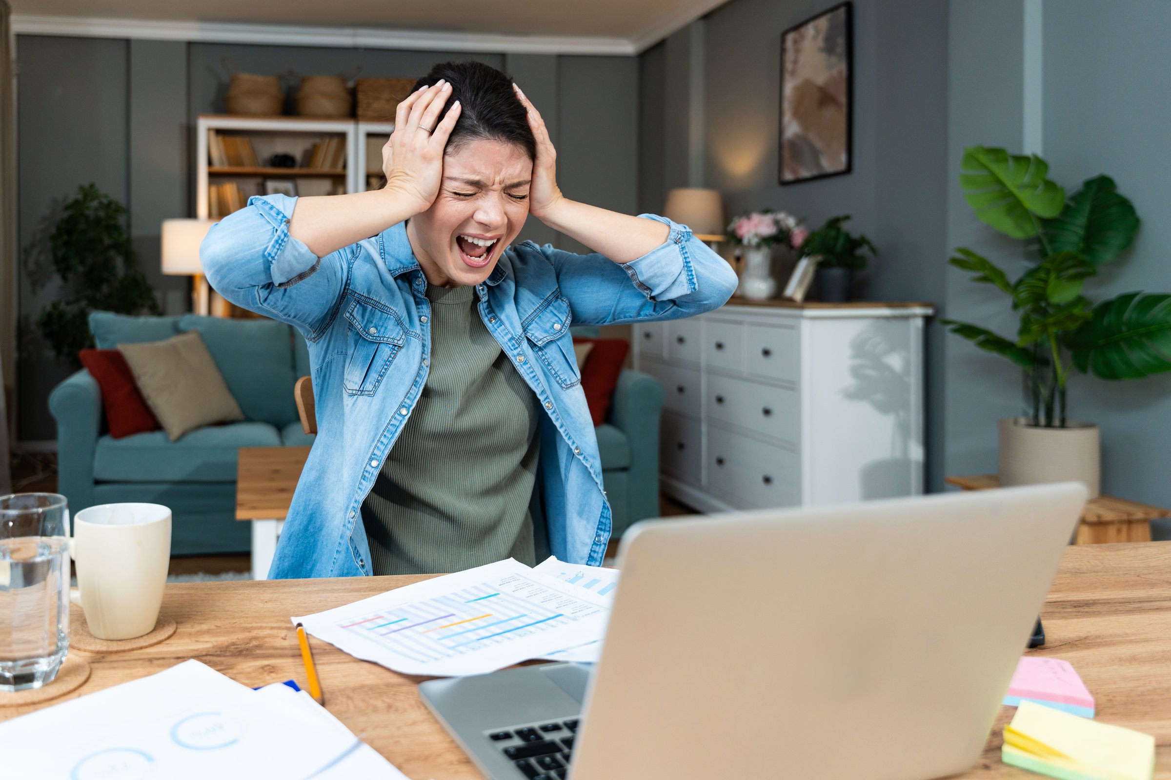Young angry stressed business woman working from home on laptop computer, having issues with client or employee. Mad and frustrated small company owner female, trouble in work, system crash.