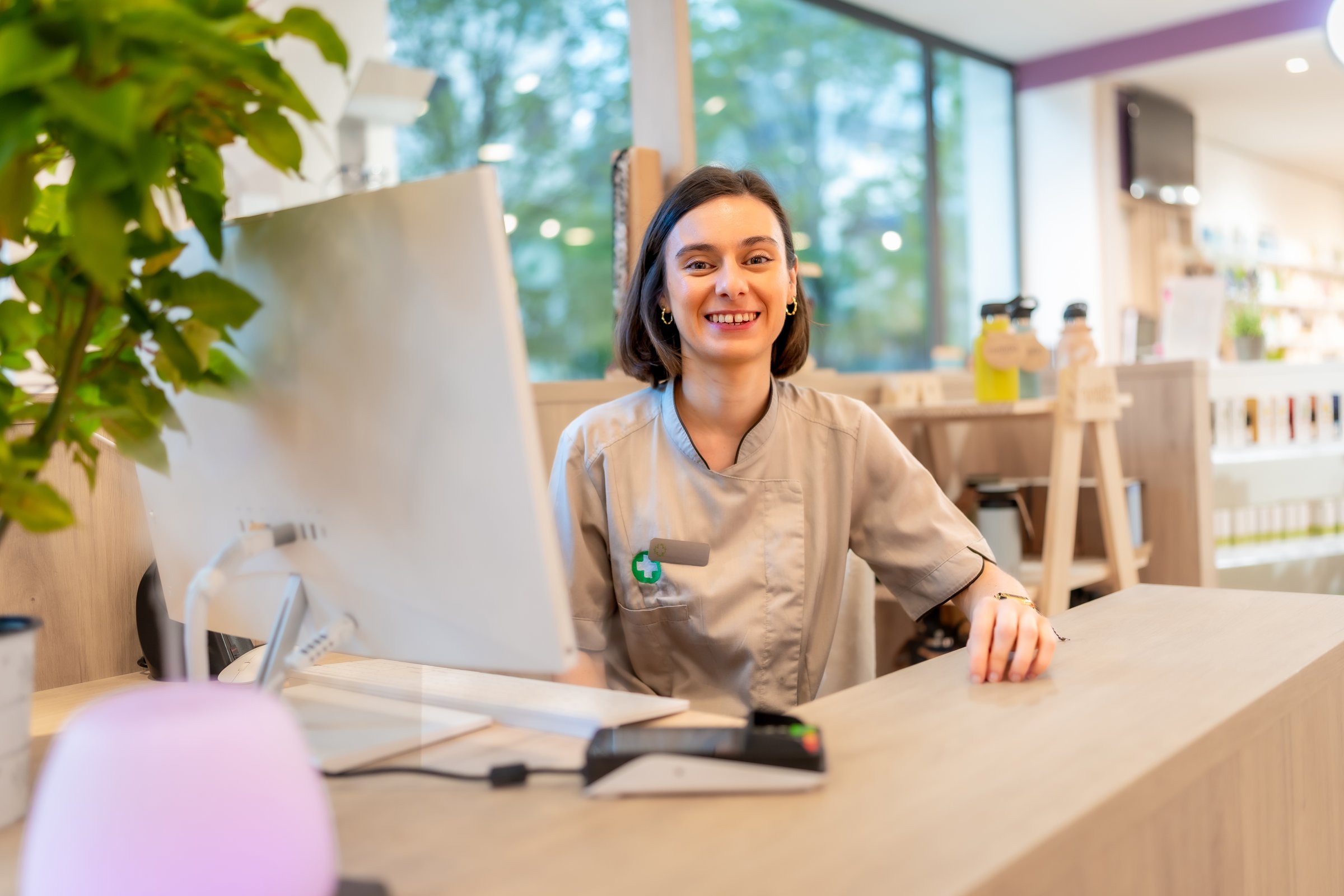Cheerful young caucasian saleswoman smiling at camera while working on the counter of a pharmacy store
