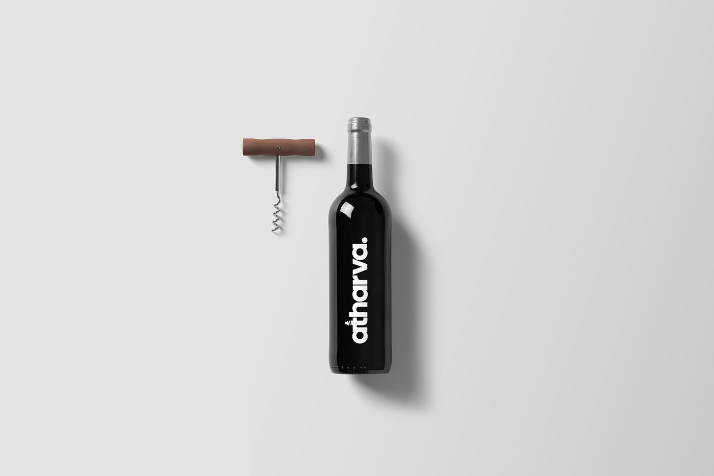 Wine bottle with atharva label next to a corkscrew on a light gray background.
