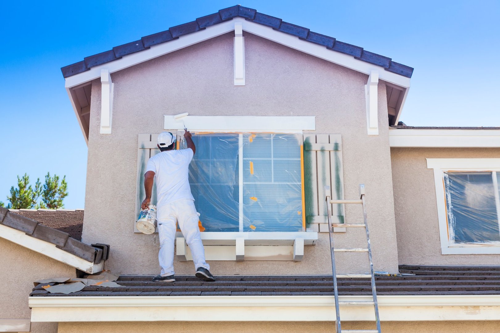 Hombre pintando el exterior de una casa con un jardín