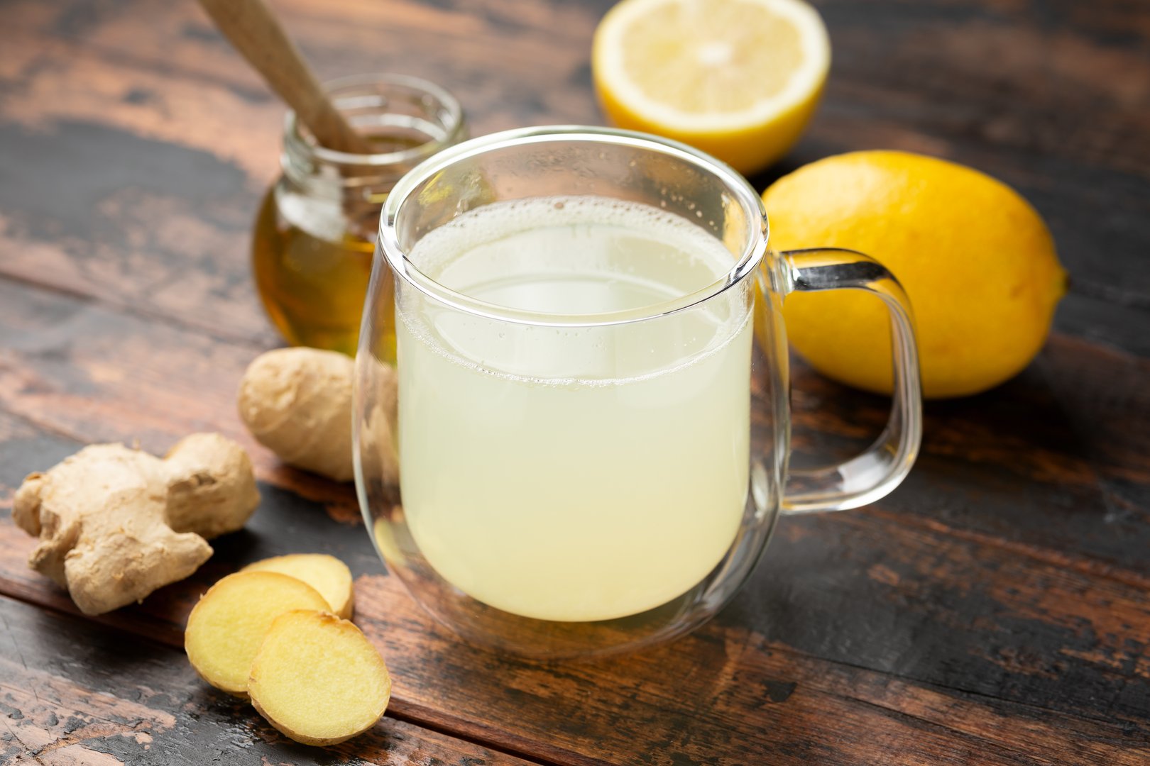 Glass cup of lemon and ginger tea and honey rustic wooden background.