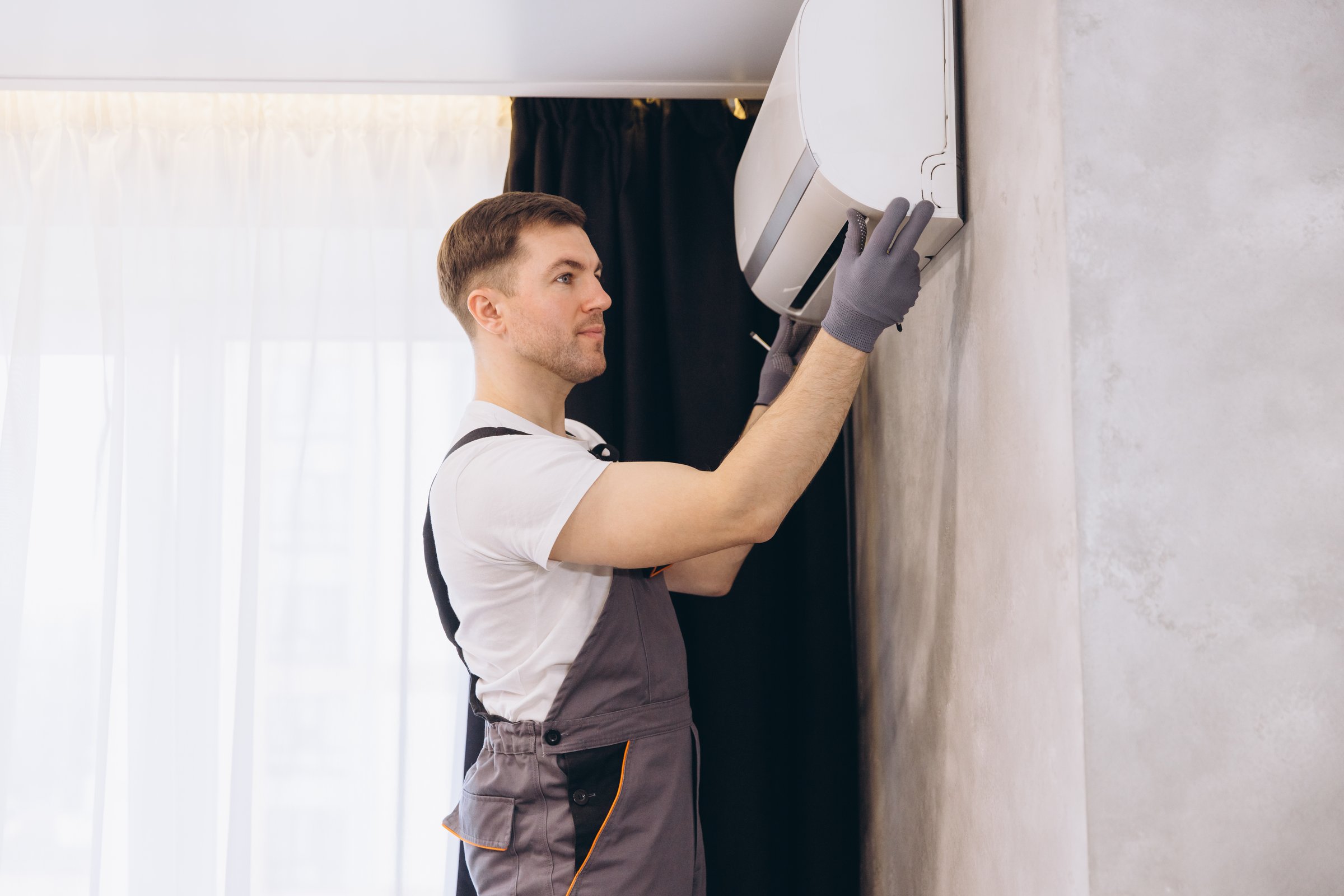 Male technician working on a HVAC system during maintenance or installation of a new air conditioner unit in a residential building