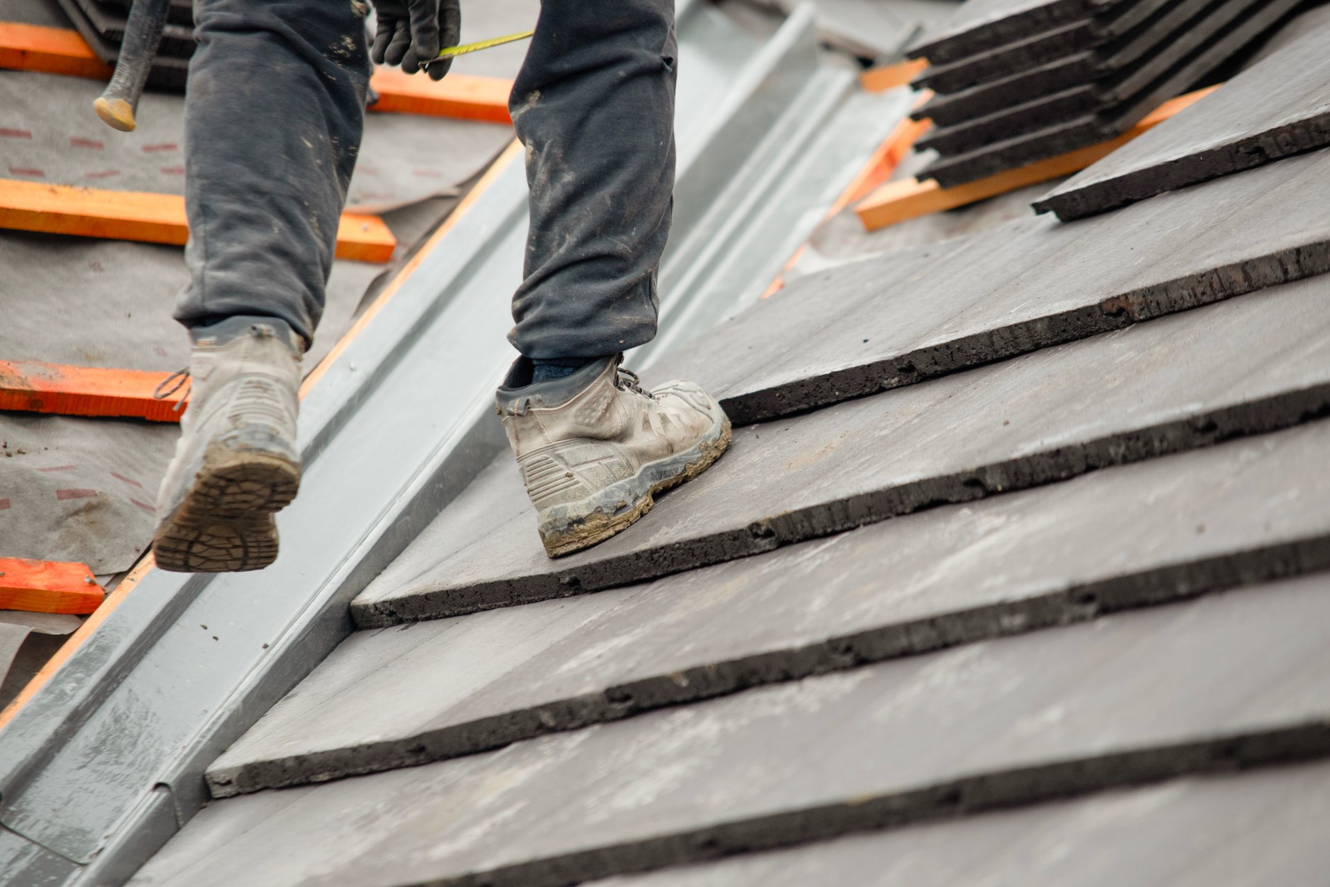 Builder placing roof tiles on sloped surface