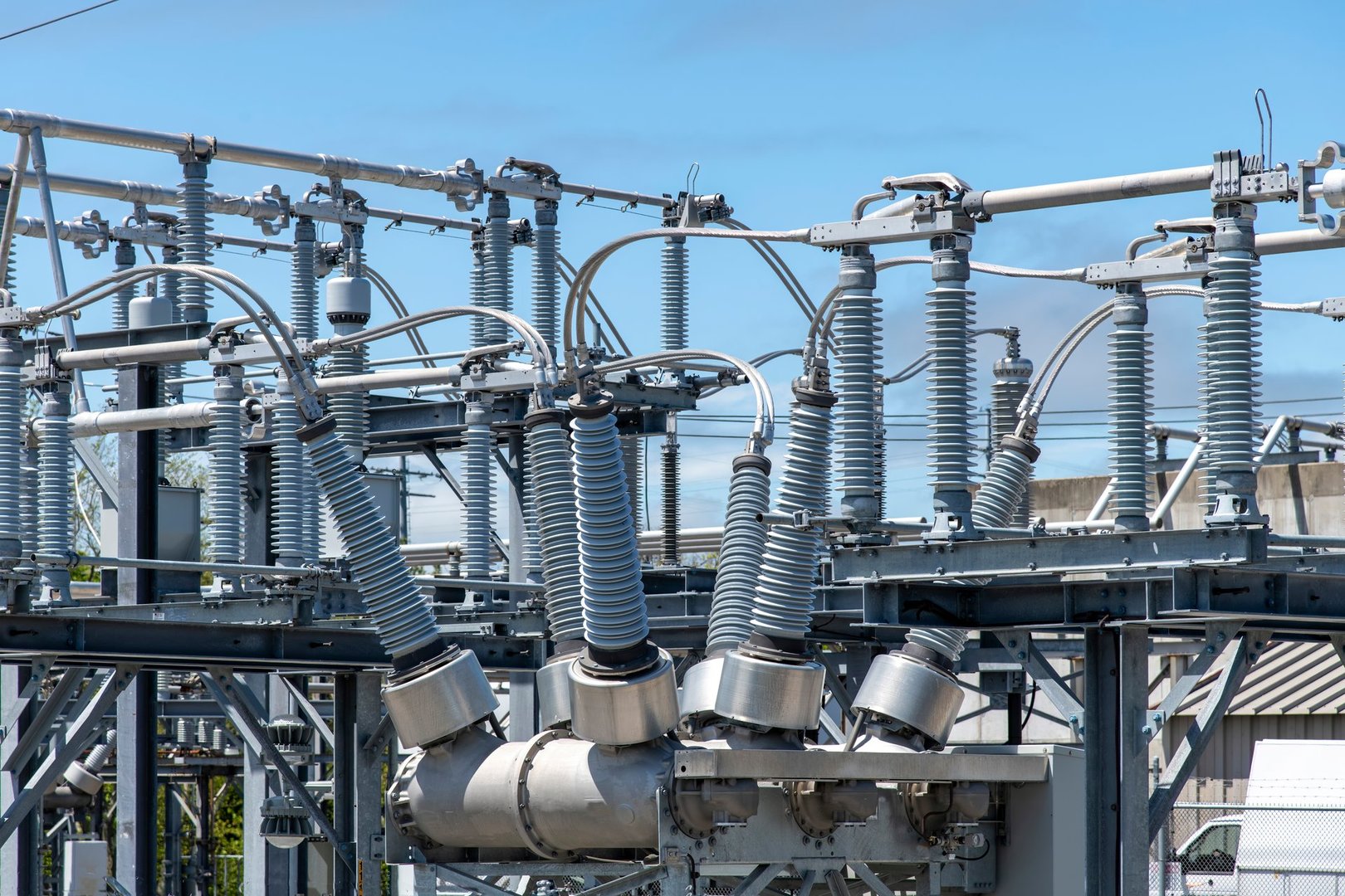 Close up view of some high-voltage bushings on a utility transformer at an electrical substation which allows an electrical conductor to pass safely through a conducting barrier