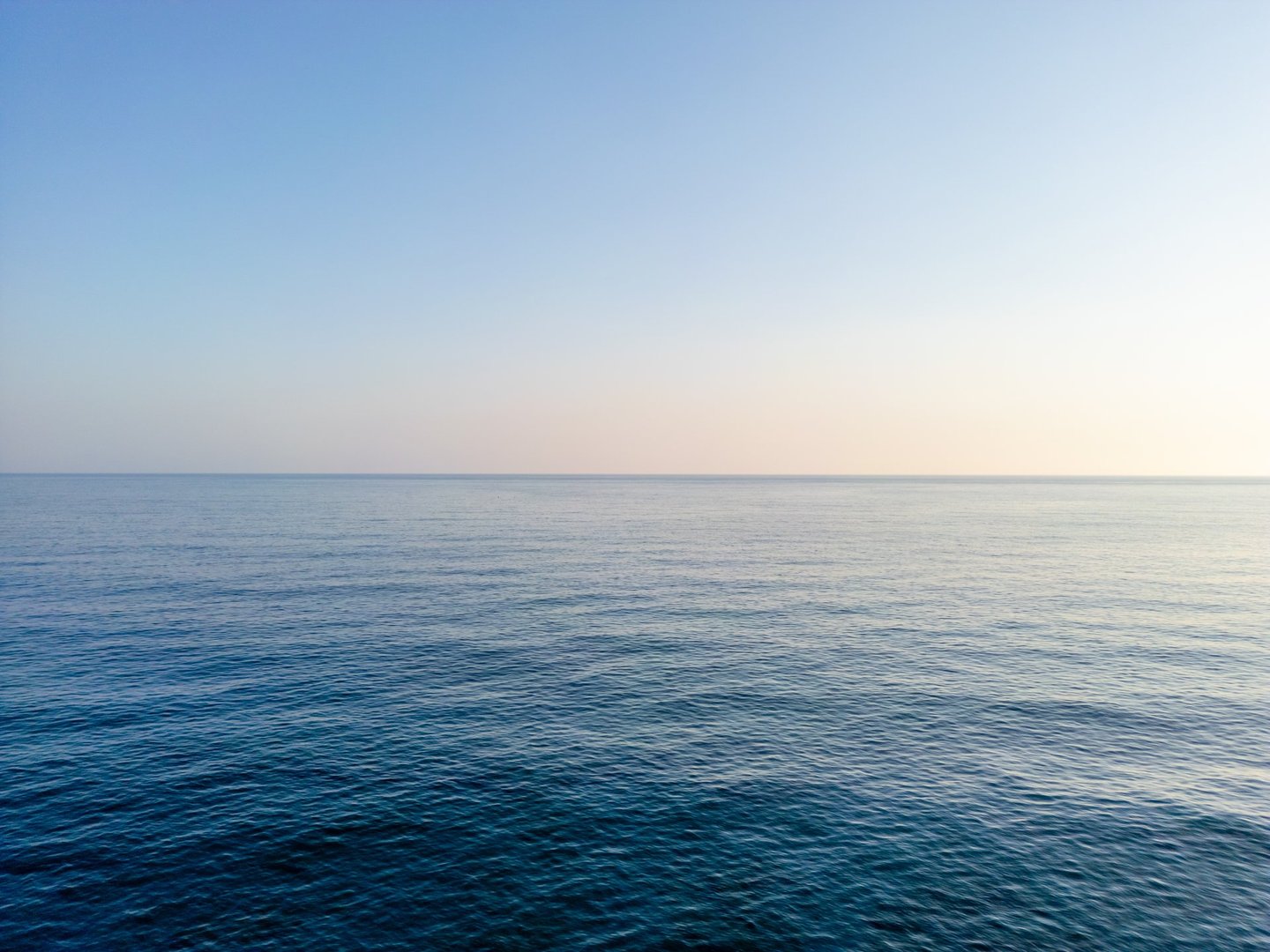 Aerial drone shot of the sea over the horizon, blue sea and clouds scenery