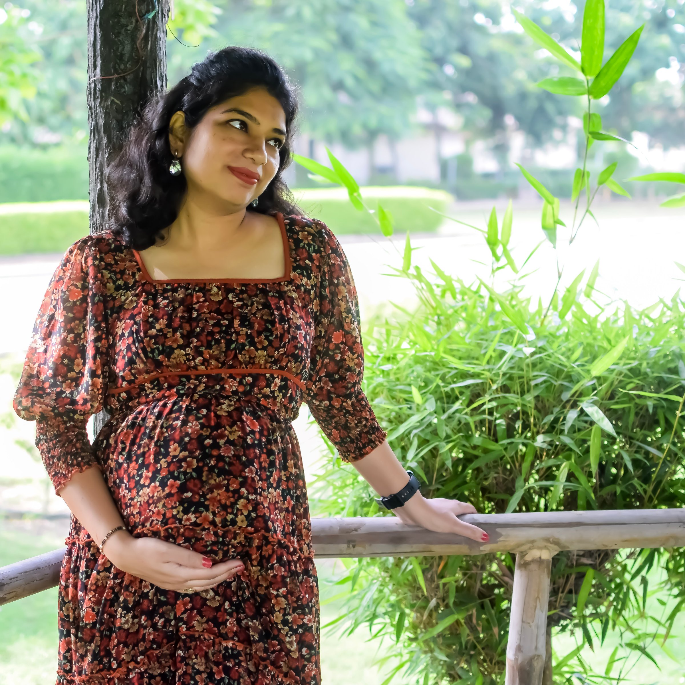 A pregnant Indian lady poses for outdoor pregnancy shoot and hands on belly, Indian pregnant woman puts her hand on her stomach with a maternity dress at society park, Pregnant outside maternity shoot