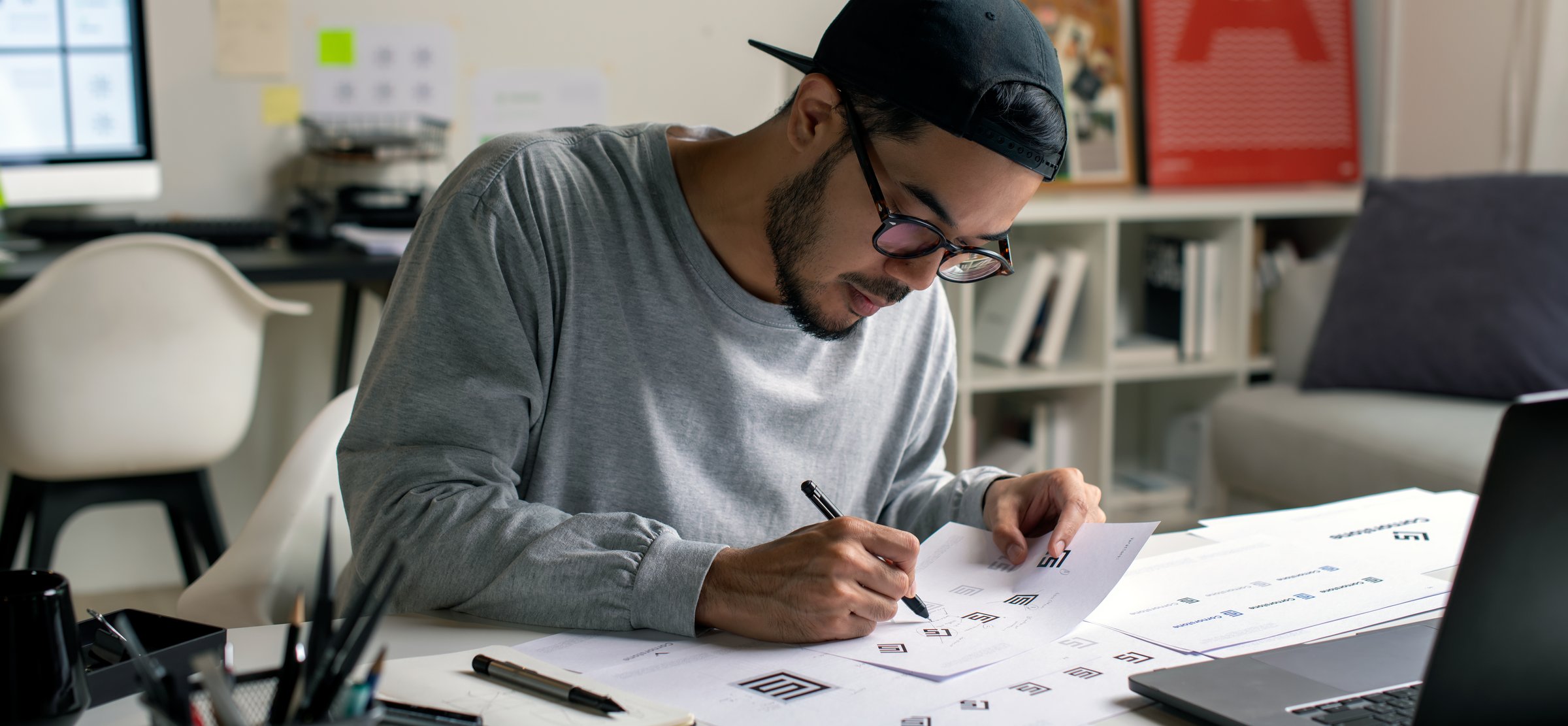 Candid shot of Asian graphic designer inspecting logo designs, using computers, designing logos, and showcasing the corporate identity and logo design process.