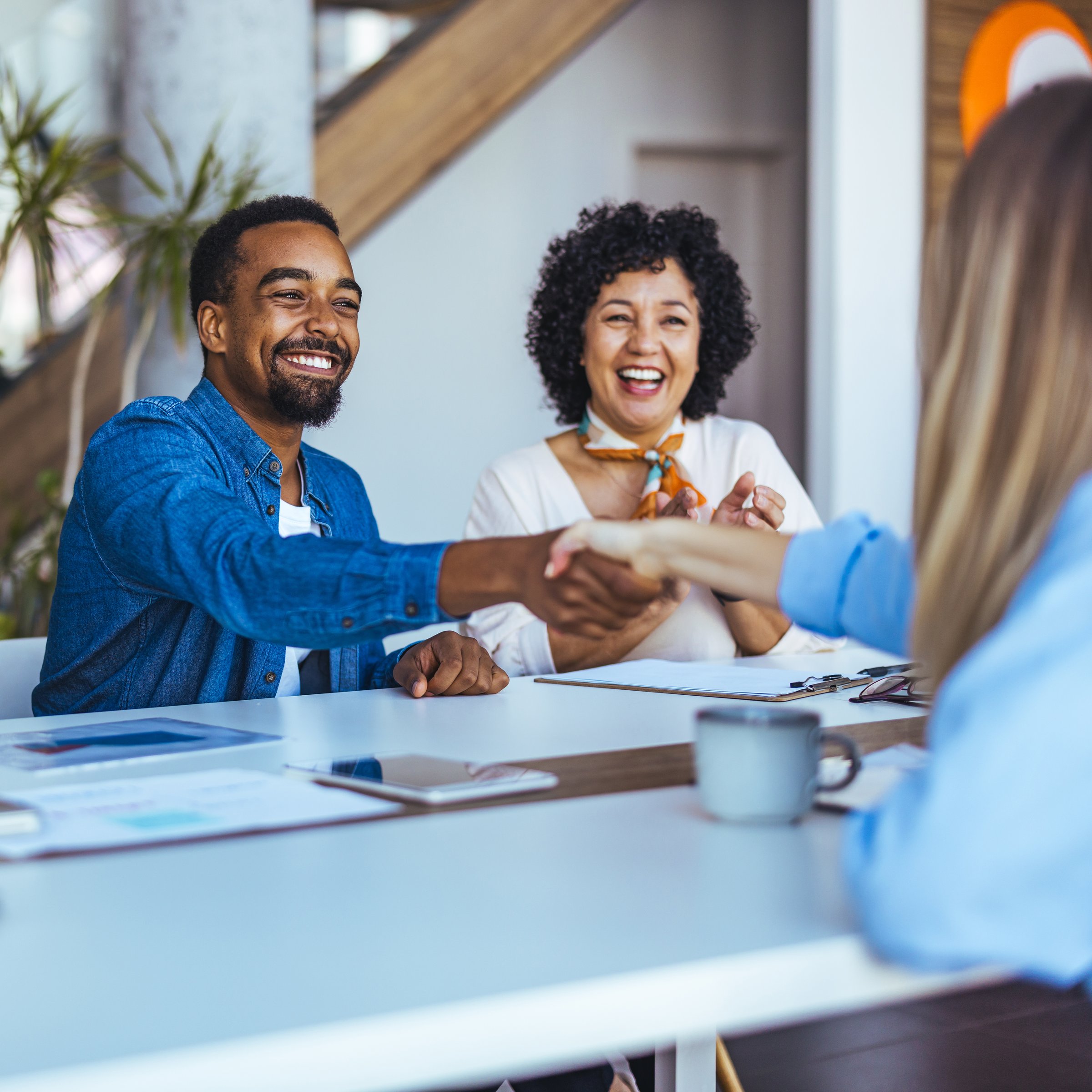 Joyful colleagues exchanging handshakes in a modern office setting, surrounded by collaborative energy and productive dialogue.