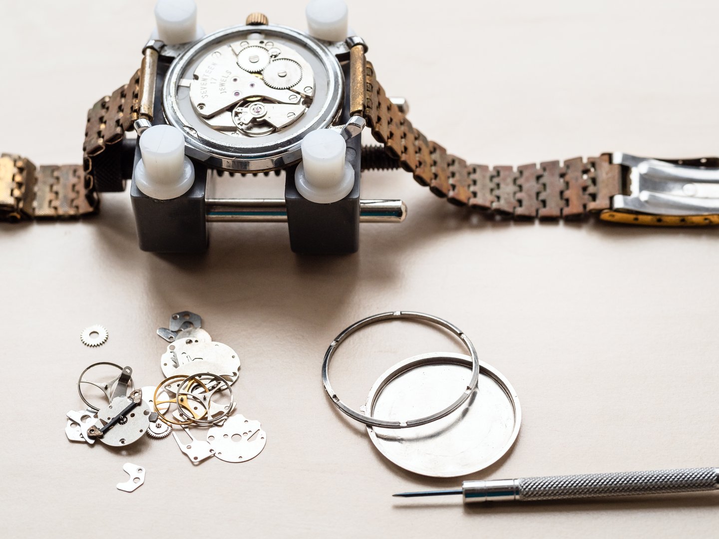spare parts for old wristwatch on wooden table in watchmaker workshop