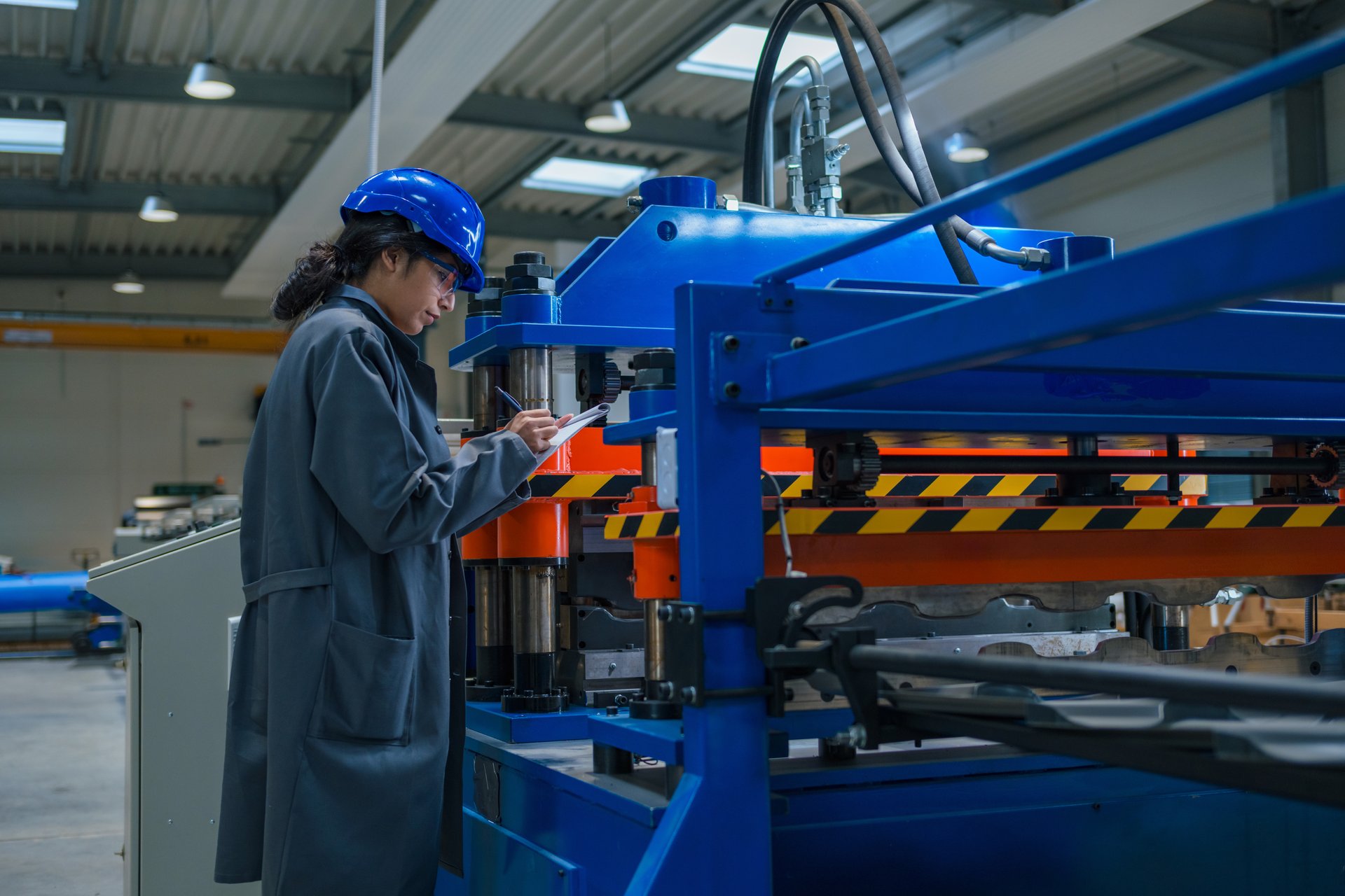 Indian woman maintenance engineer in an industry plant, carefully looking into checklist and machinery with a flashlight, close up shot.