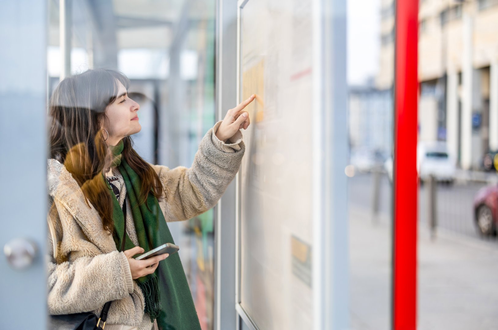 Young woman checking the timetable at a bus stop in the city