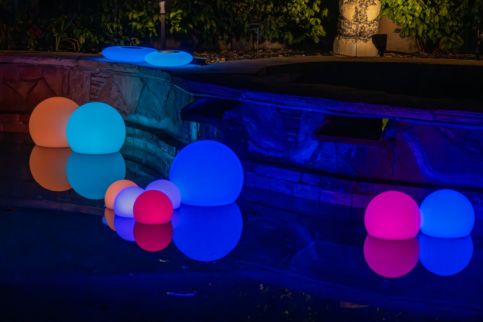 A few outdoor ambience lights floating around a swimming pool