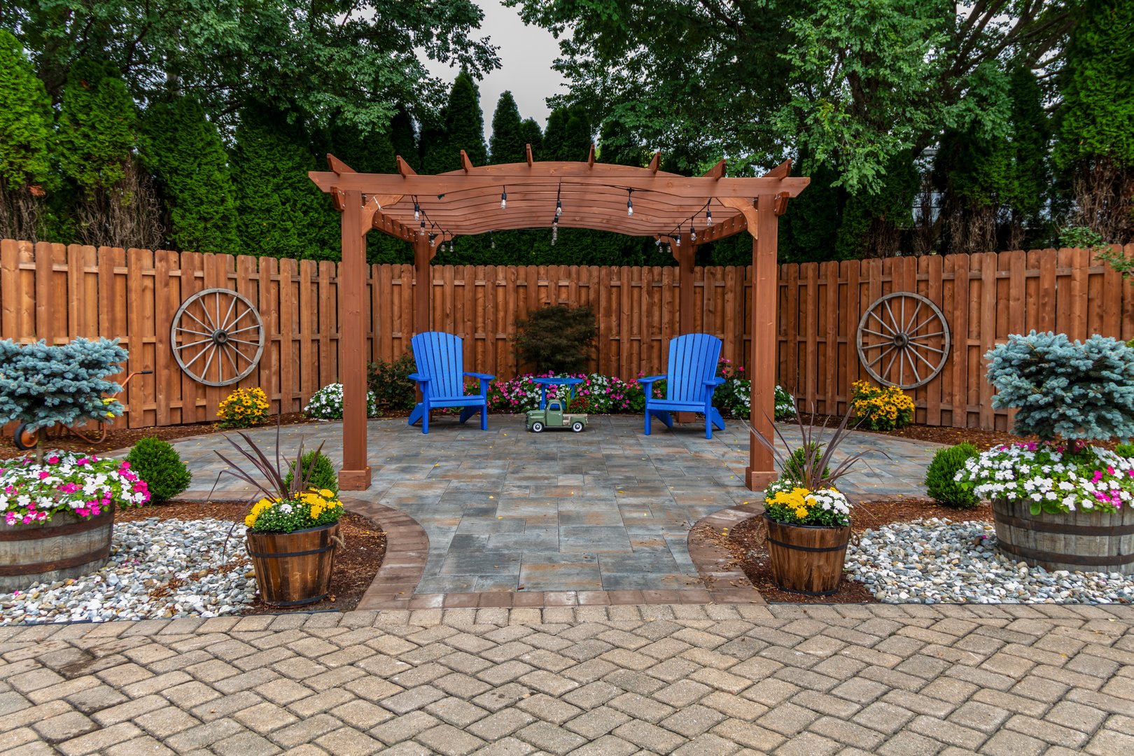 Wooden pergola on pavers landscape design with select ornamental flowers and evergreens backyard oasis landscape architecture