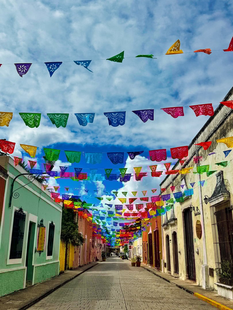 Traditional papel picado decorative paper flags fly over the colourful pastel coloured shops of trendy Calzada de los Frailes street in historic Valladolid town,a Pueblo Magico city in Yucatan,Mexico