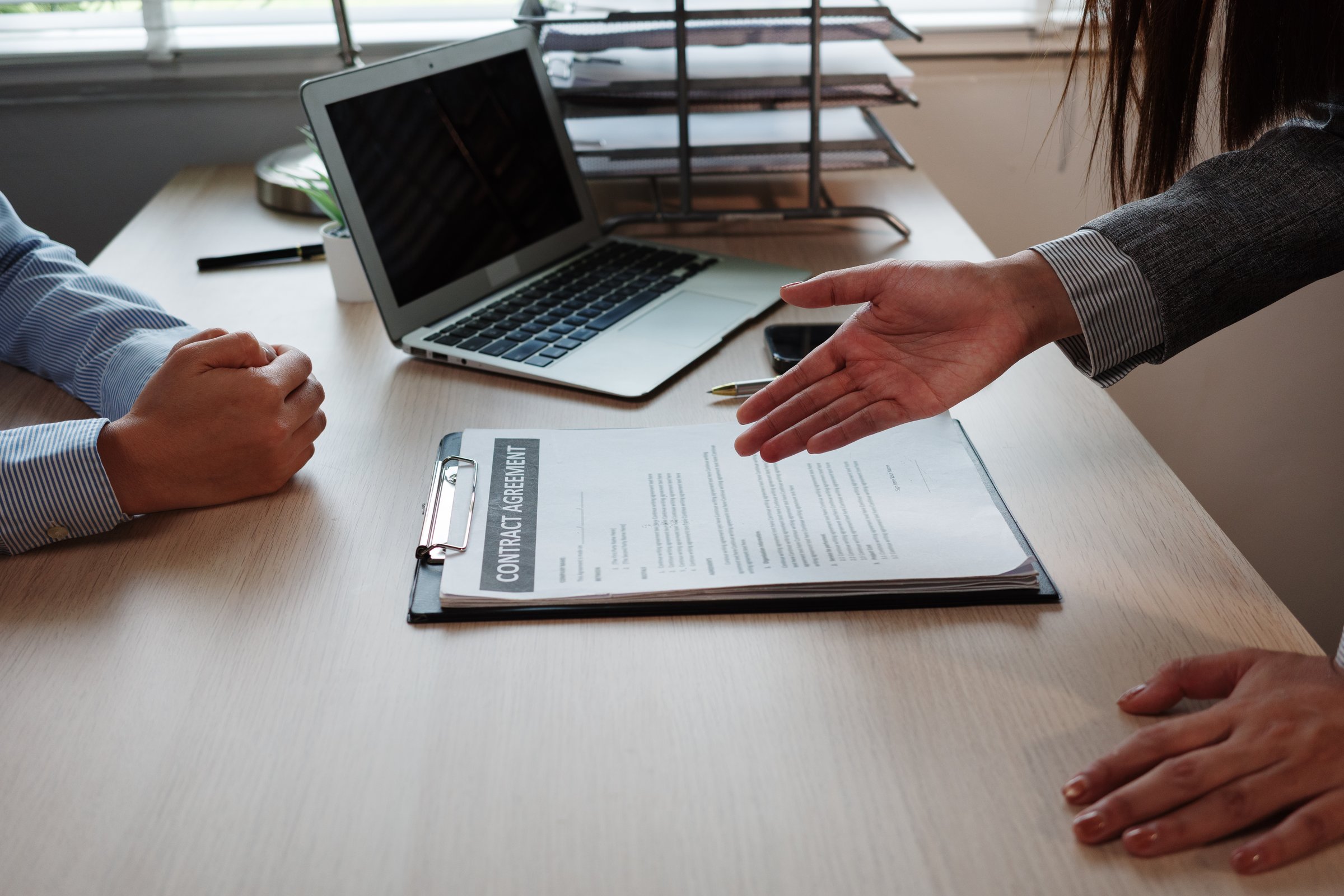 Businesswoman presenting a contract agreement to a businessman in an office setting, highlighting collaboration and professional discussions