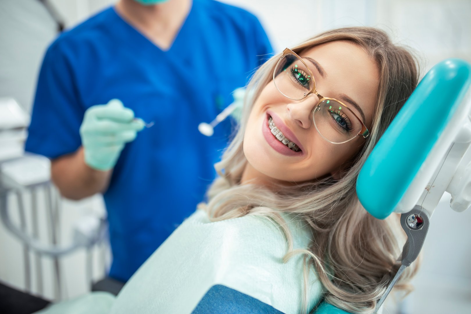 Beautiful young woman with braces having dental treatment at dentist's office