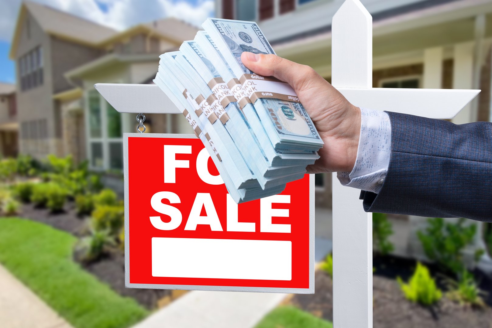 Buyer Handing Over Cash for House with Home and For Sale Real Estate Sign Behind