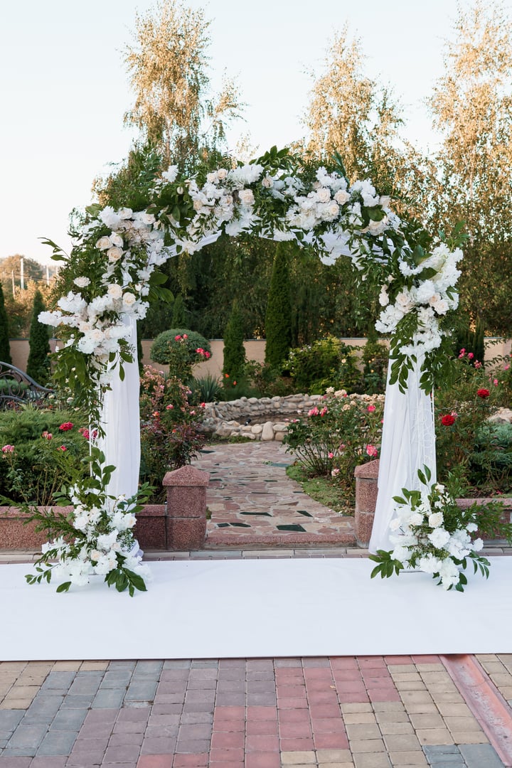 Elegant Floral Wedding Arch Surrounded by Lush Garden Landscape.