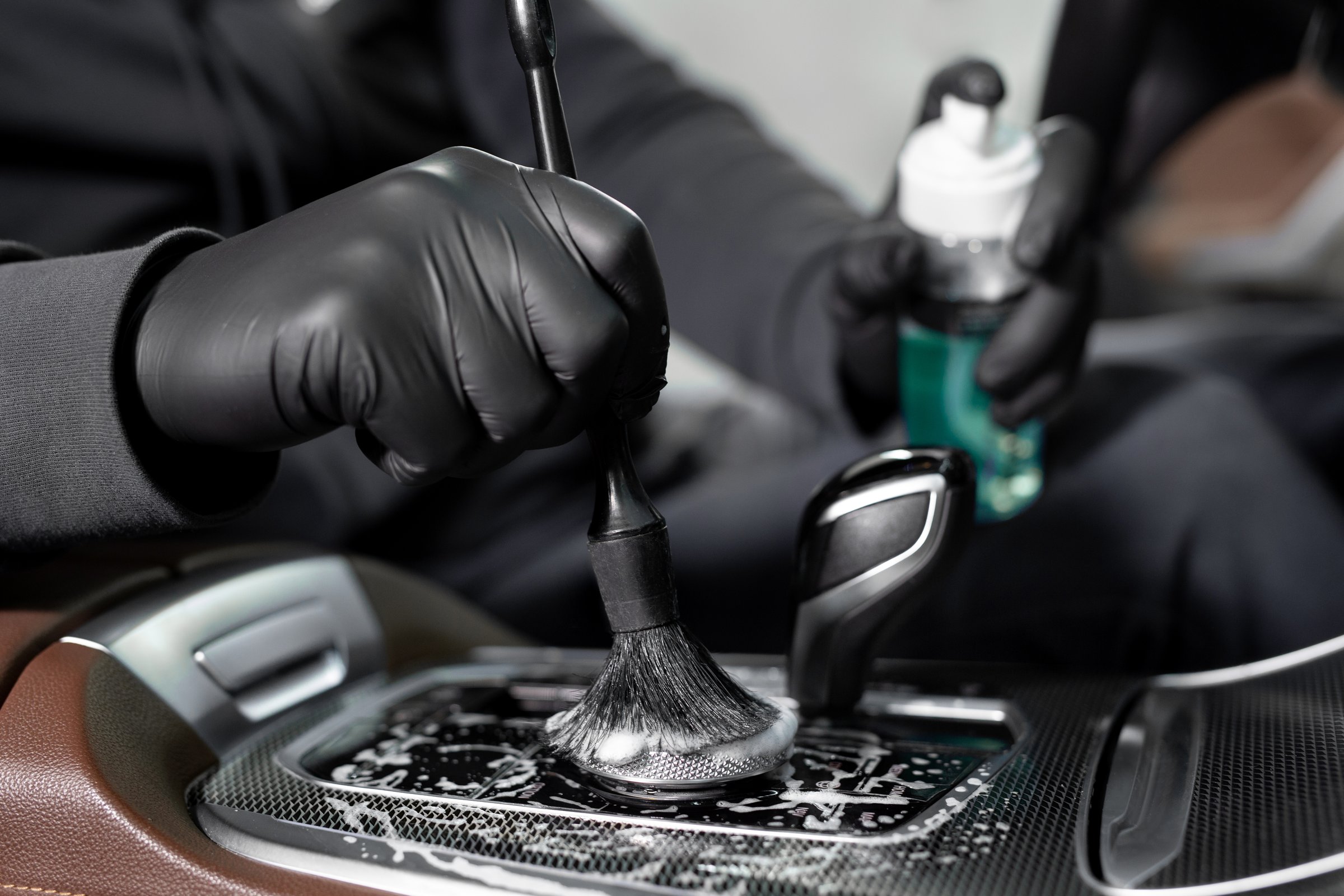 The process of applying foam and detergent with a brush. A car wash service worker cleans the car inside.