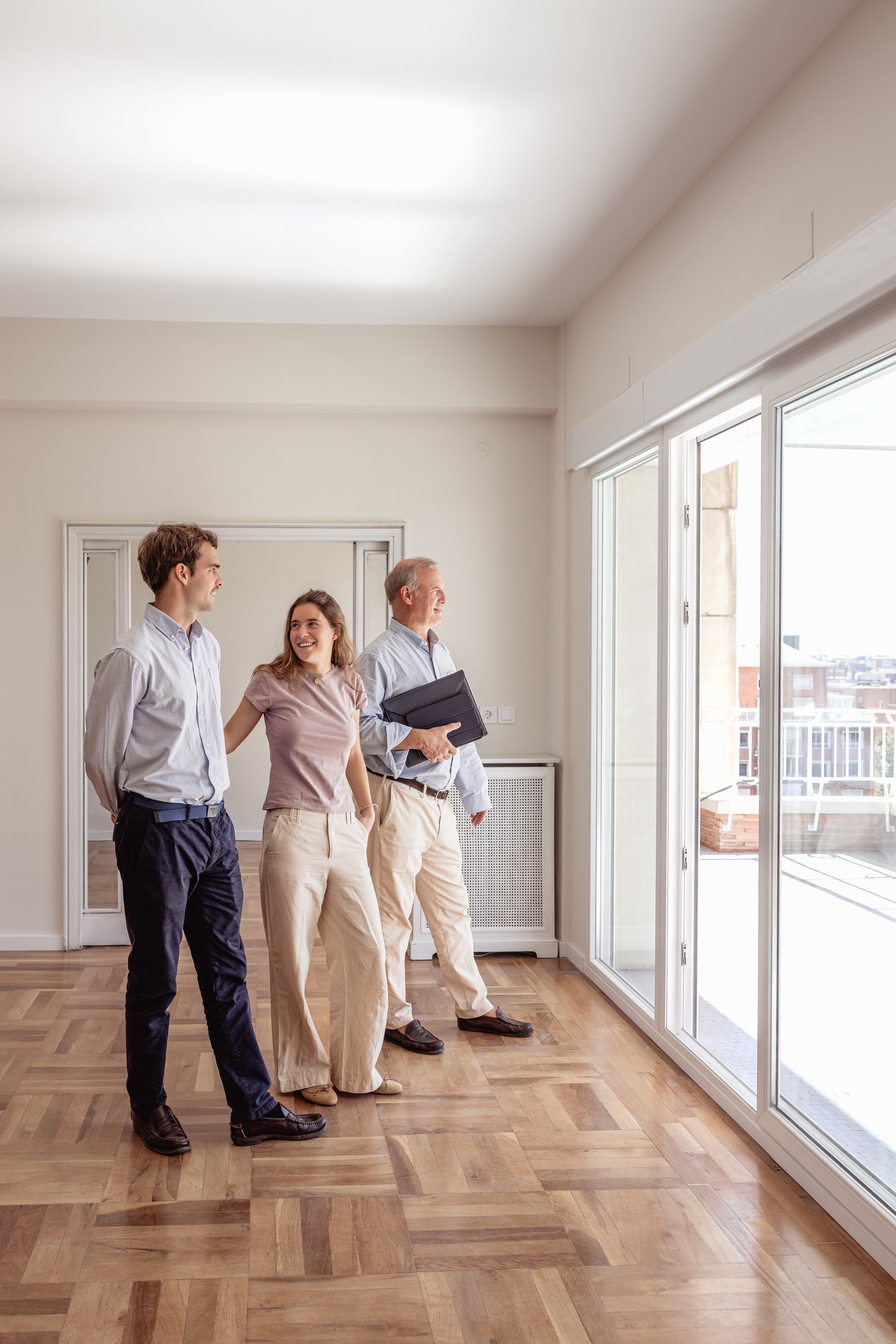 Real estate agent showing empty apartment to happy young couple looking for a new home