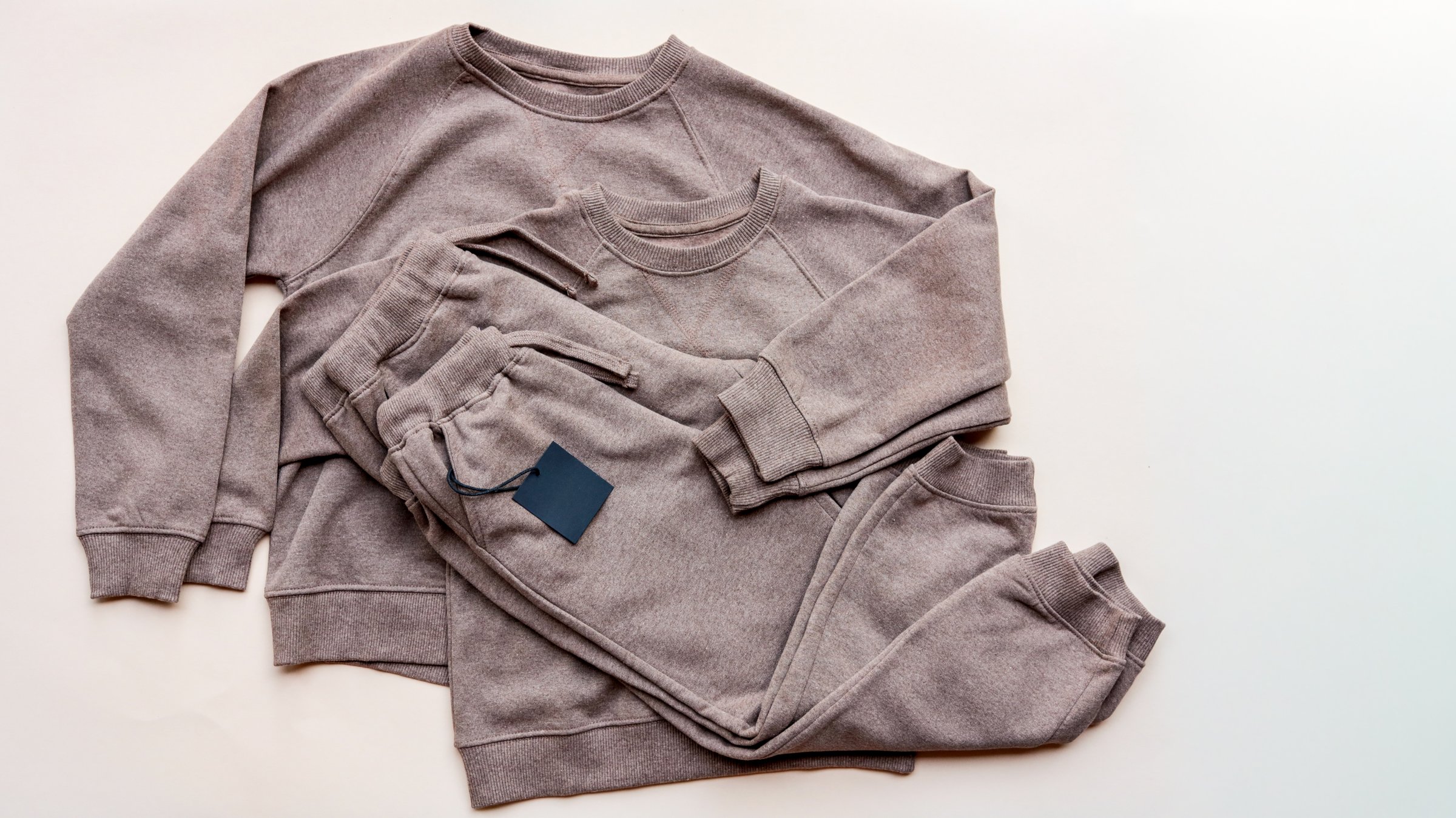 A stylish sweatsuit set, including a sweatshirt and sweatpants, is neatly arranged on a light-colored surface, perfect for casual wear.