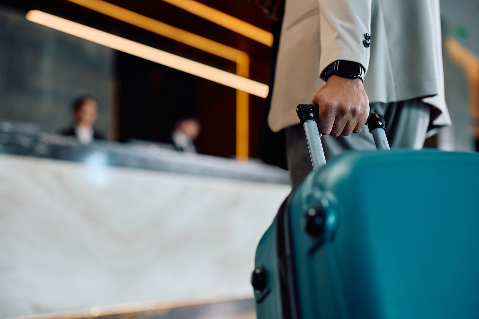 Close up of African American man with a luggage entering in a hotel.