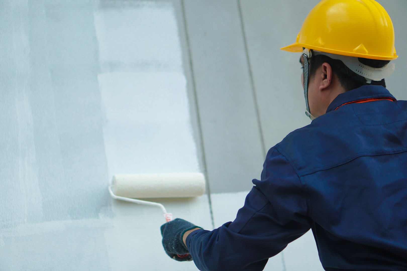 Asian construction worker painting the walls of a house