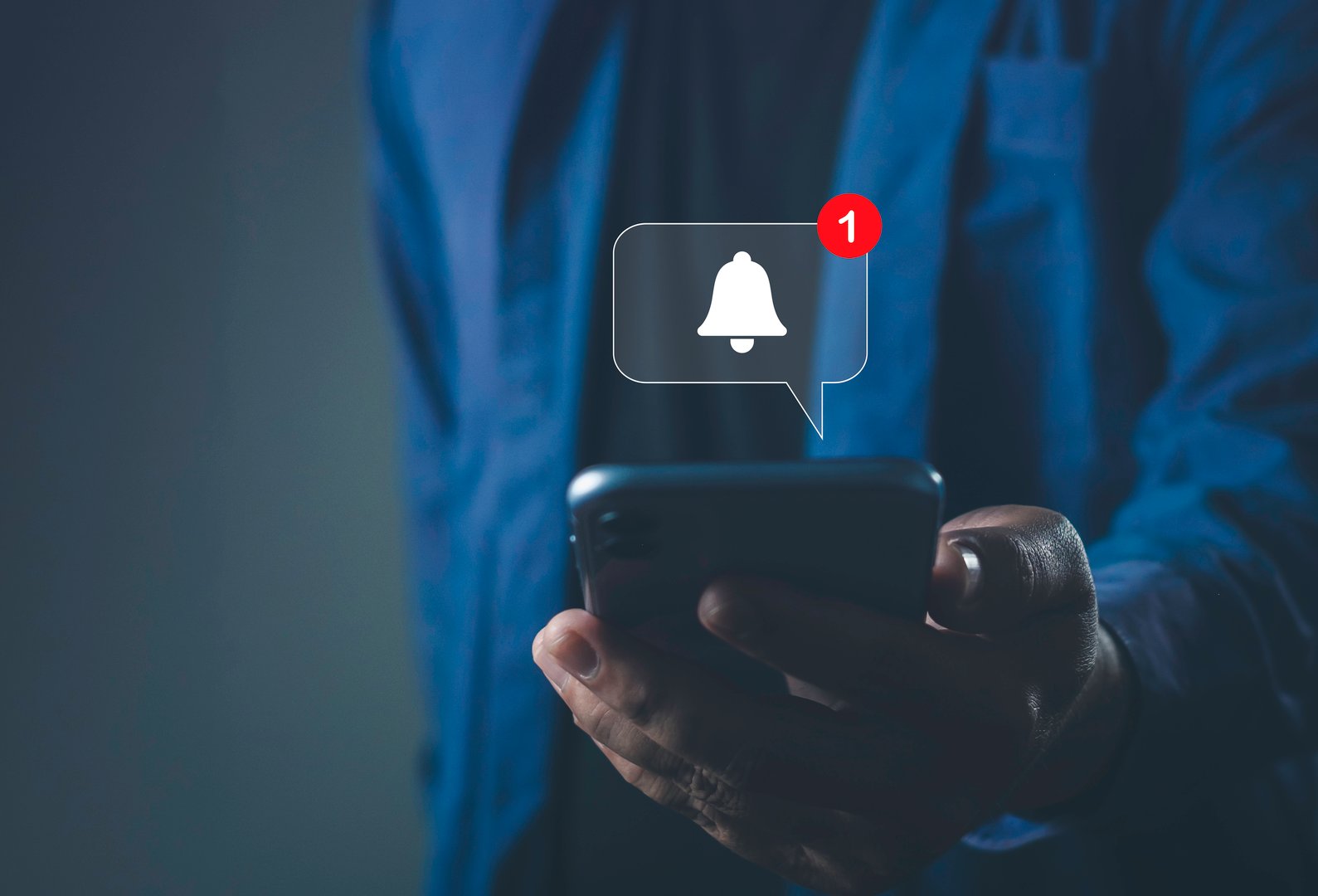 Man holding smartphone with alert notification icon, representing mobile alert, push notification, real-time update, communication, and app messaging system.