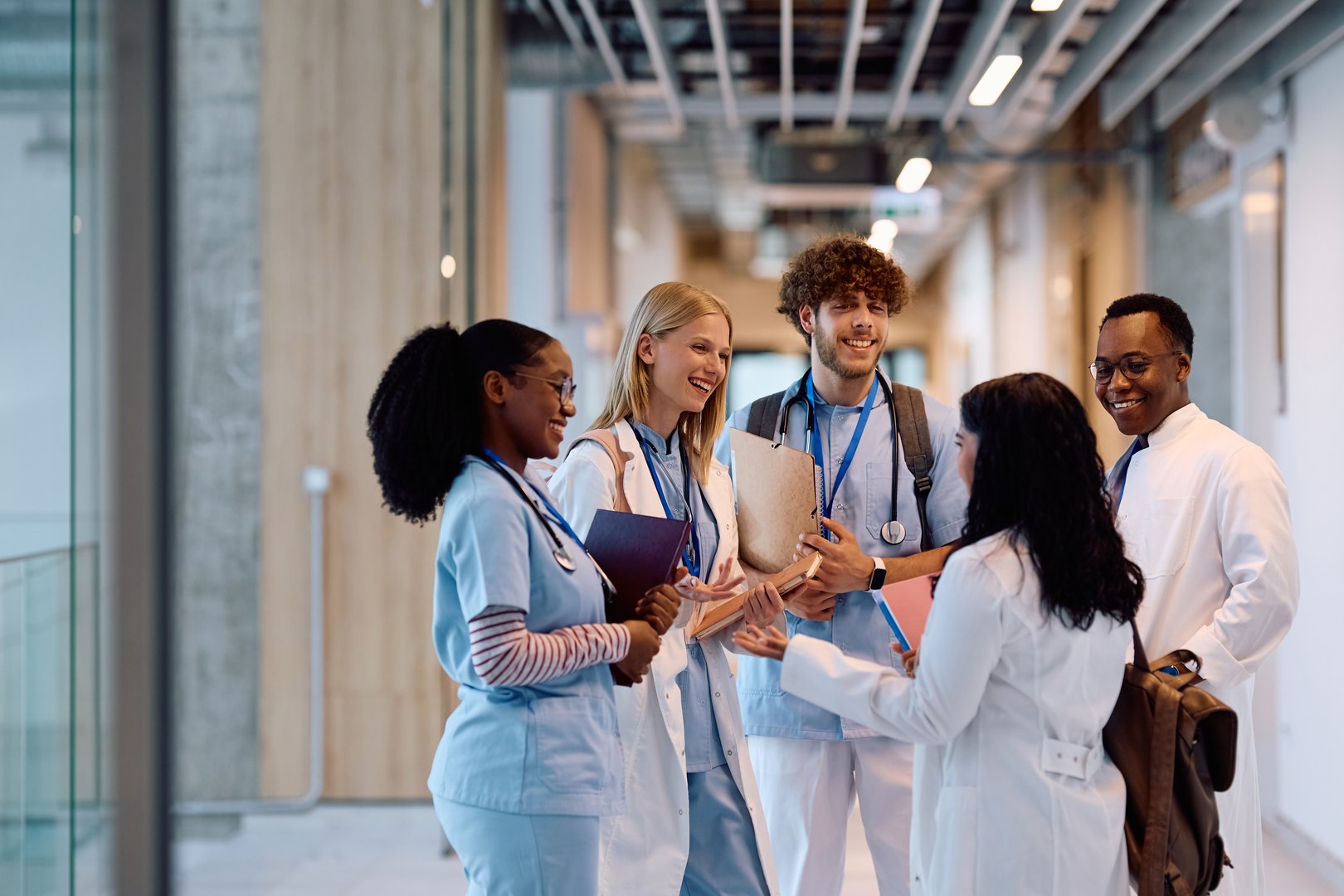Group of happy medical and nursing students talking in a hallway at the university.