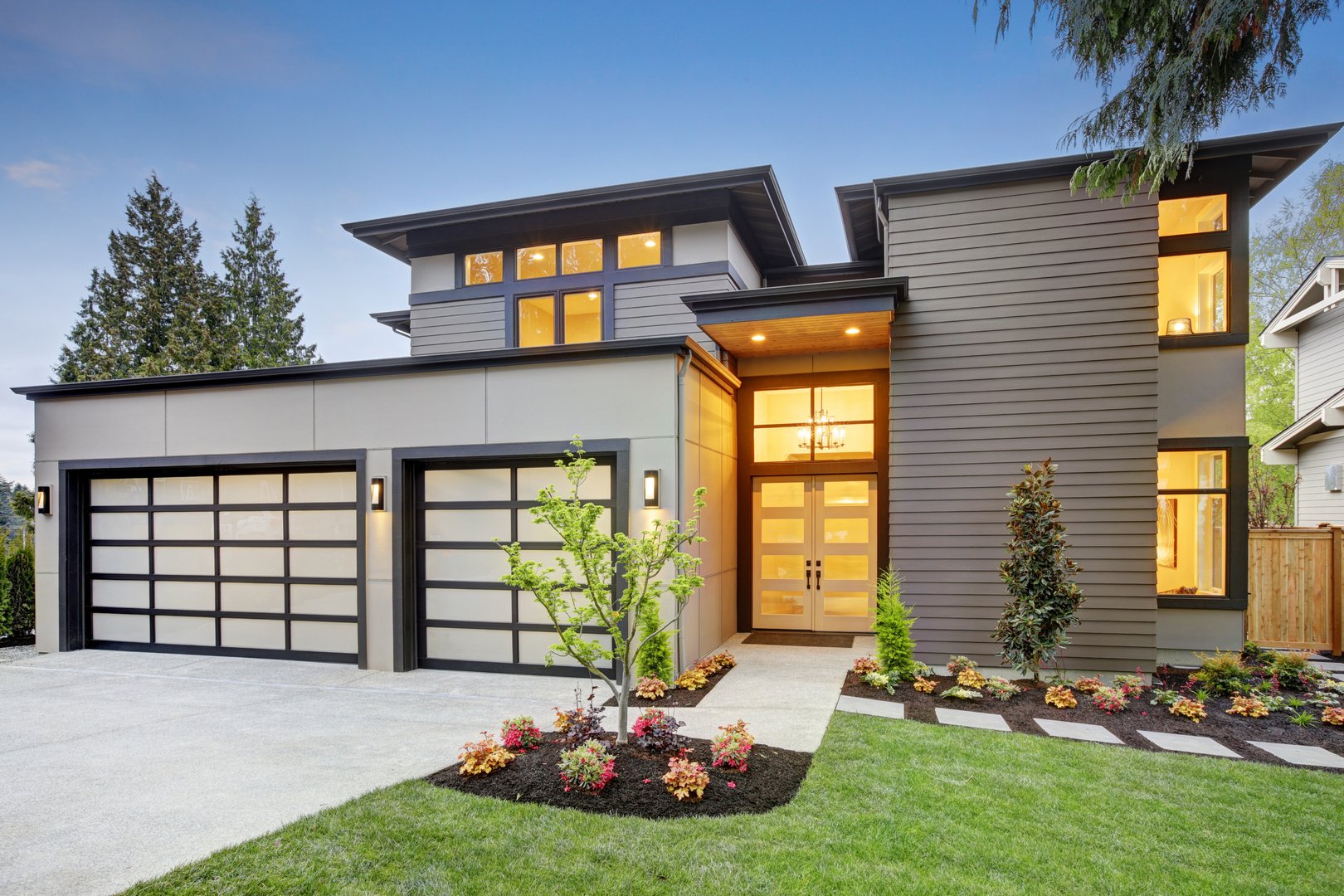 Luxurious new construction home in Bellevue, WA. Modern style home boasts two car garage spaces with glass folding doors illuminated by scones. Northwest, USA
